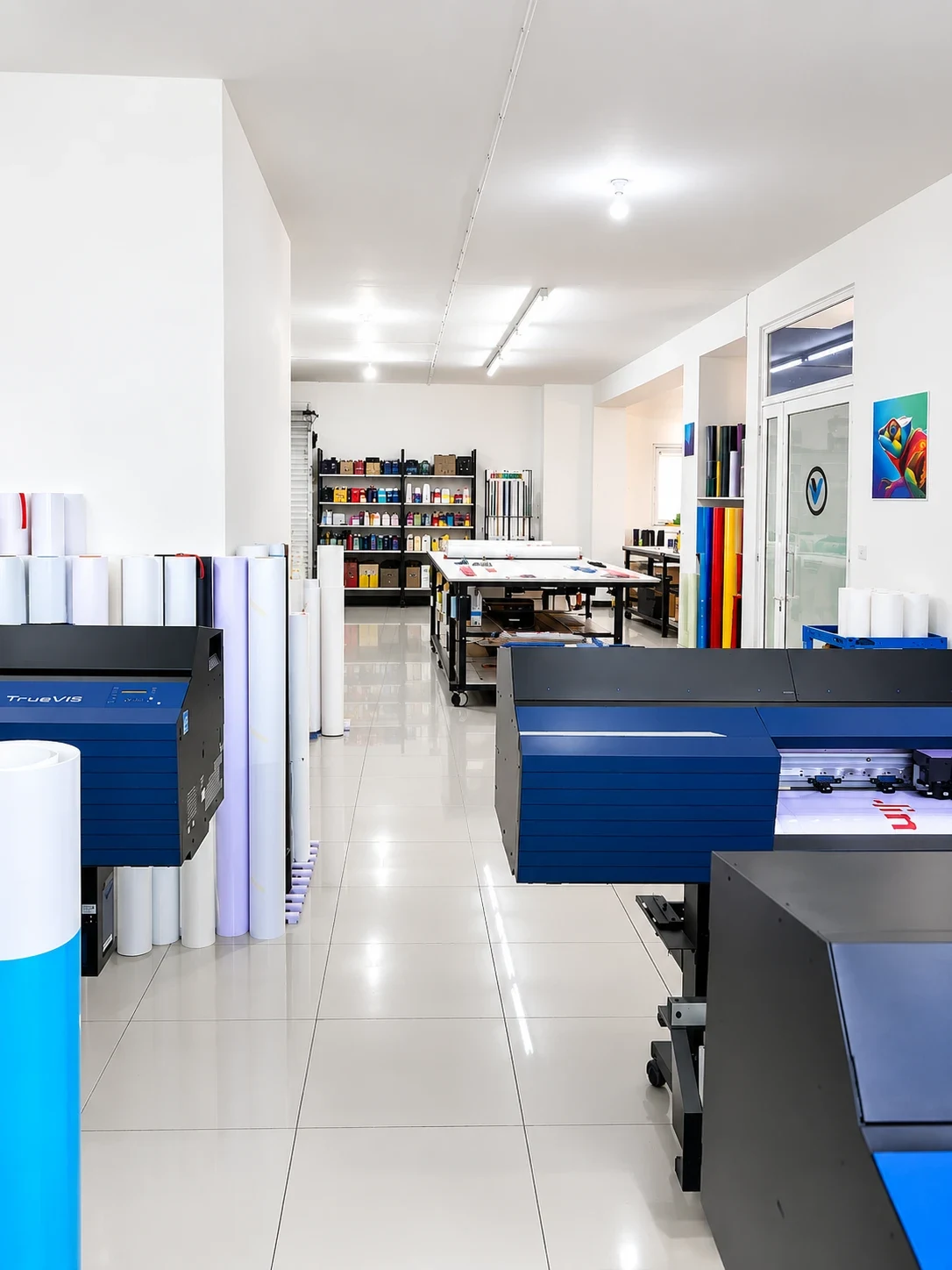 Viking Signrite print room with wide-format printers, racked vinyl rolls and a cutting table leading back to the ink shelves