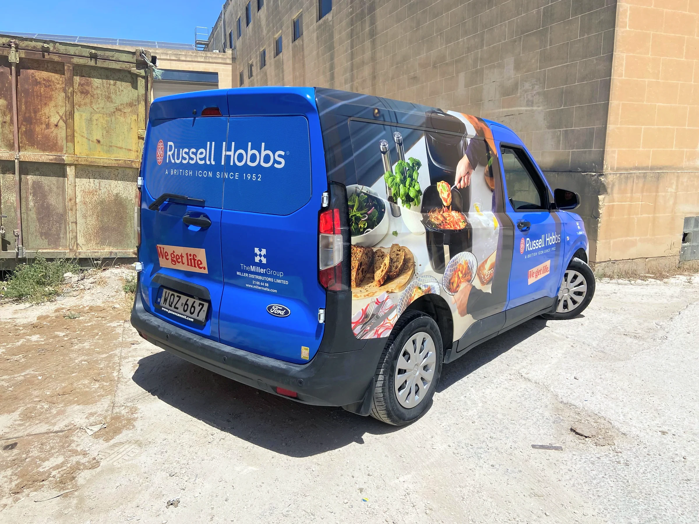 Blue compact van wrapped with kitchen and food photography along its side panel