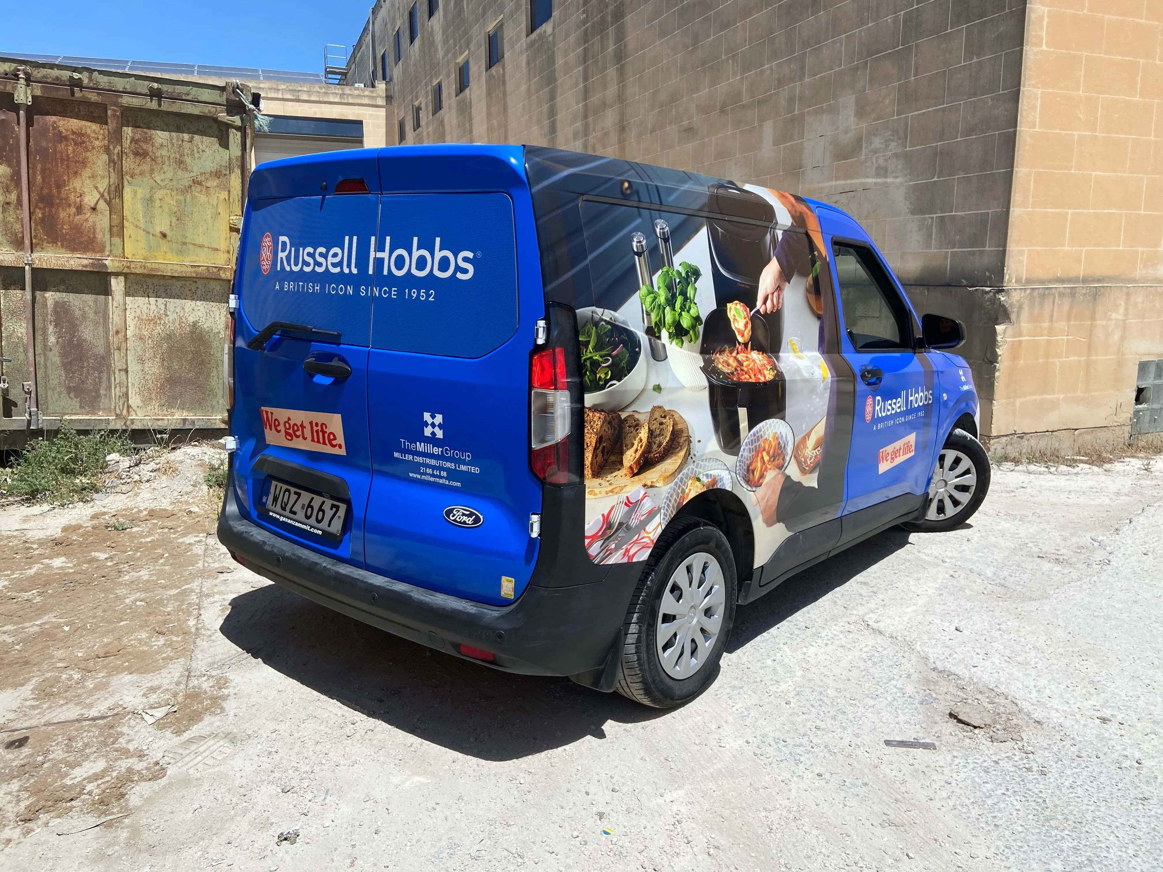 Blue compact van wrapped with kitchen and food photography along its side panel