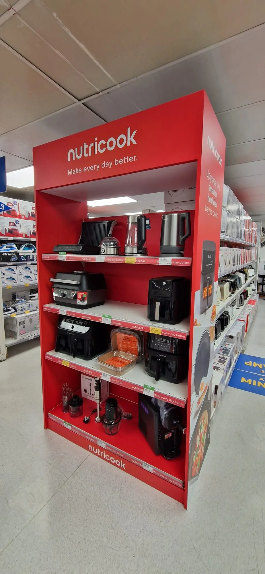 Red branded gondola end display stocked with kitchen appliances in a store aisle