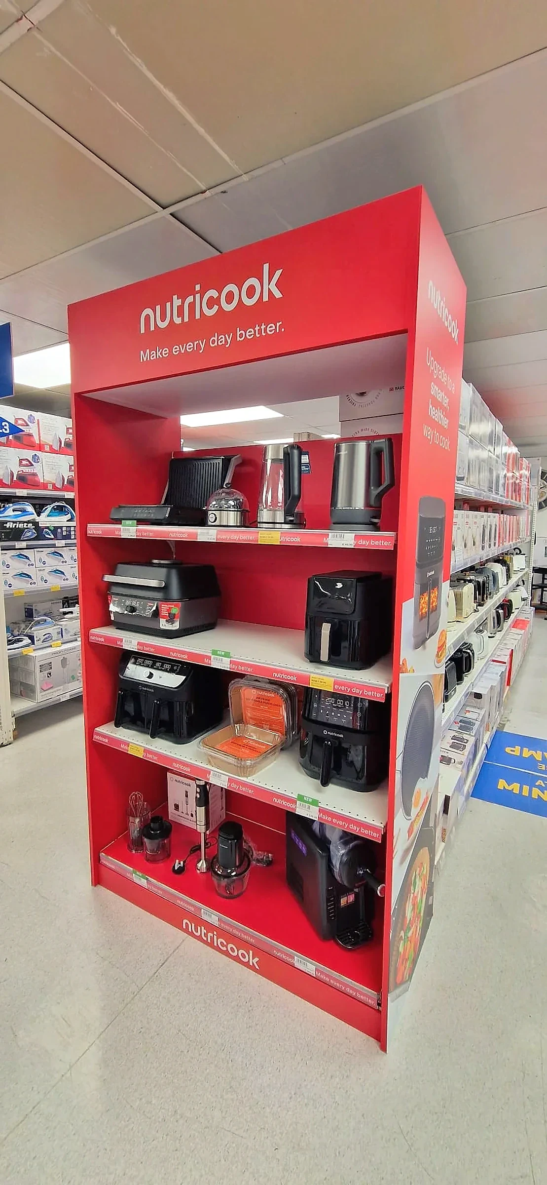 Red branded gondola end display stocked with kitchen appliances in a store aisle