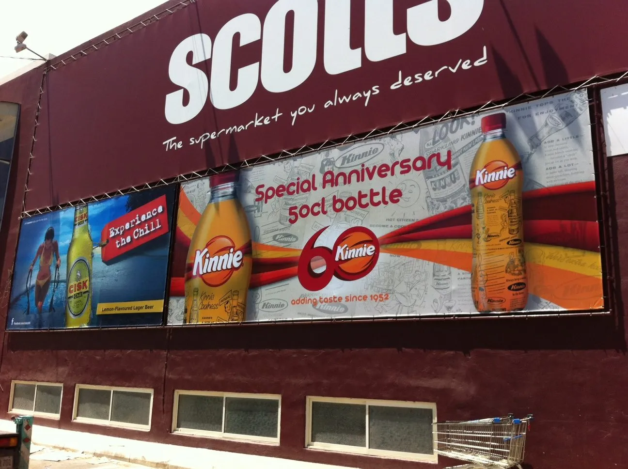 Dark red full-width printed banner with bottles across the upper storey of a building