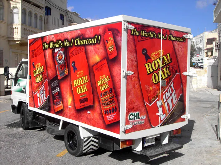 Box truck wrapped in a deep red ground with repeated product packs printed large, a banner line across the top of the rear and side, and a small contact line