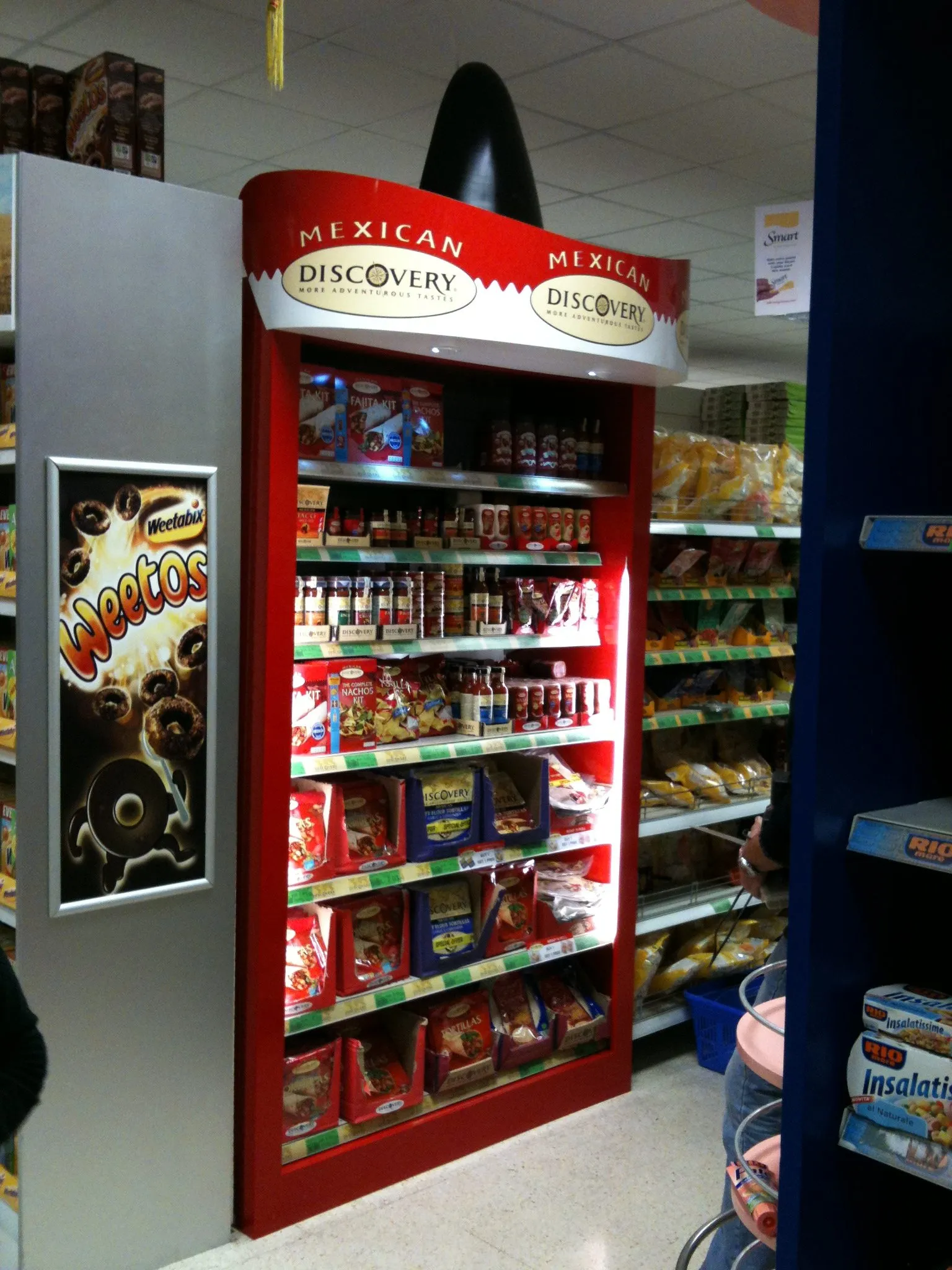 A red vending unit clad in printed panels with a branded header, stocked with packets