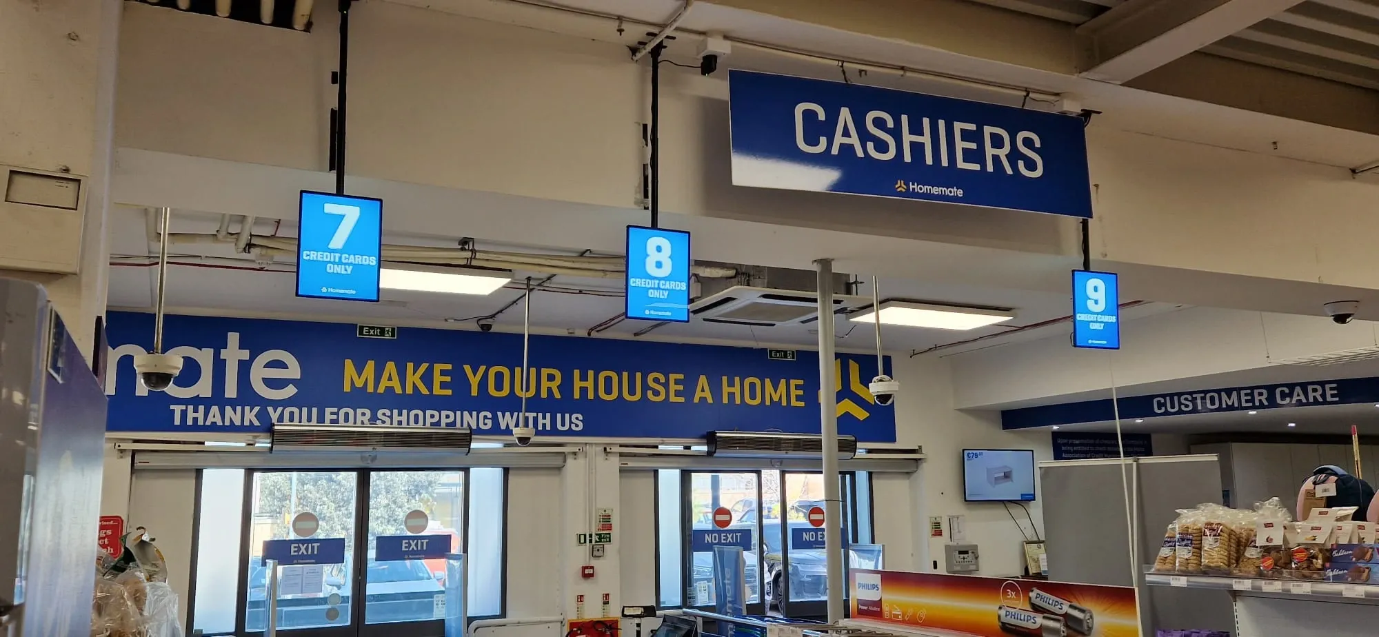 Blue overhead cashiers sign with numbered lane boxes above supermarket checkouts