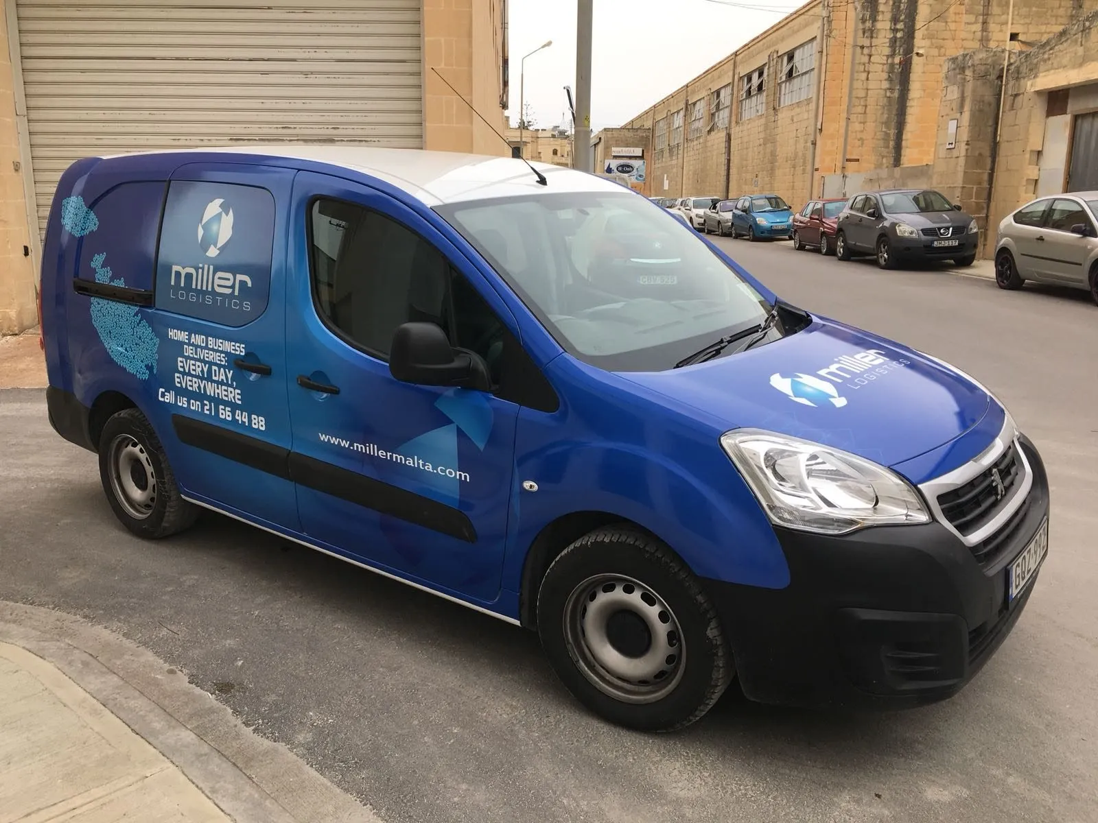Dark blue compact panel van with white livery graphics along its side, parked on a street