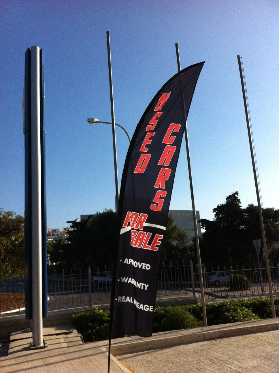 Black printed flag flying from a tall pole against a clear sky, with further poles behind