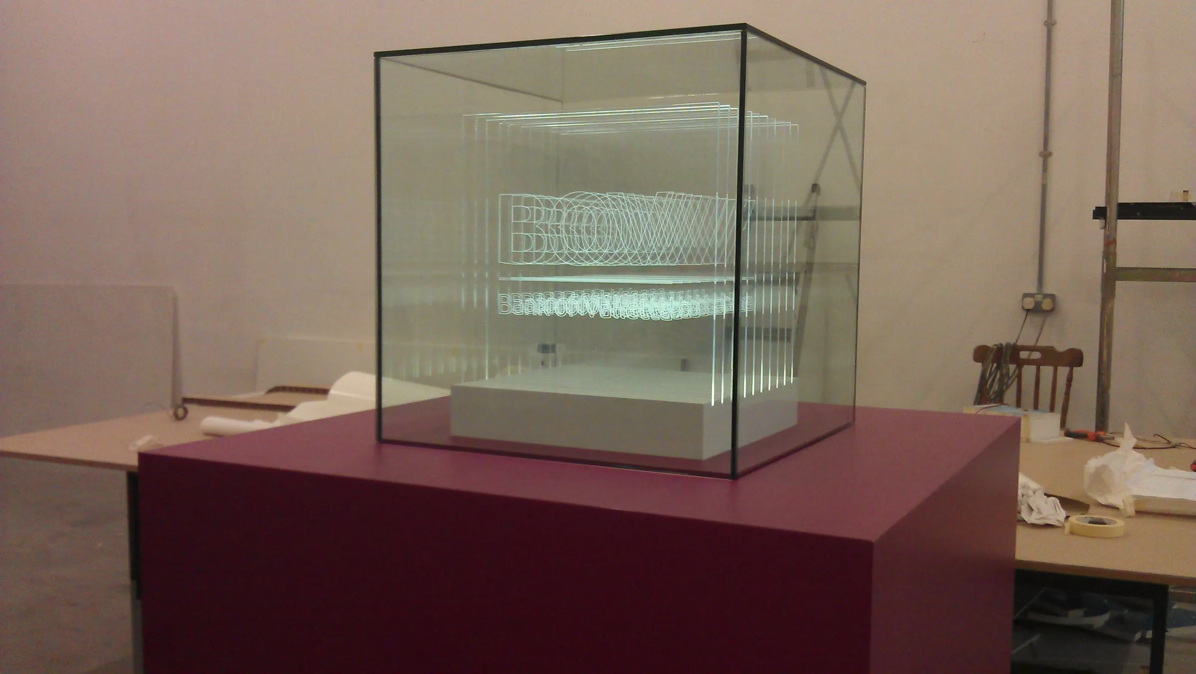Glazed display cabinet on a dark plinth in an interior, with a stepladder alongside