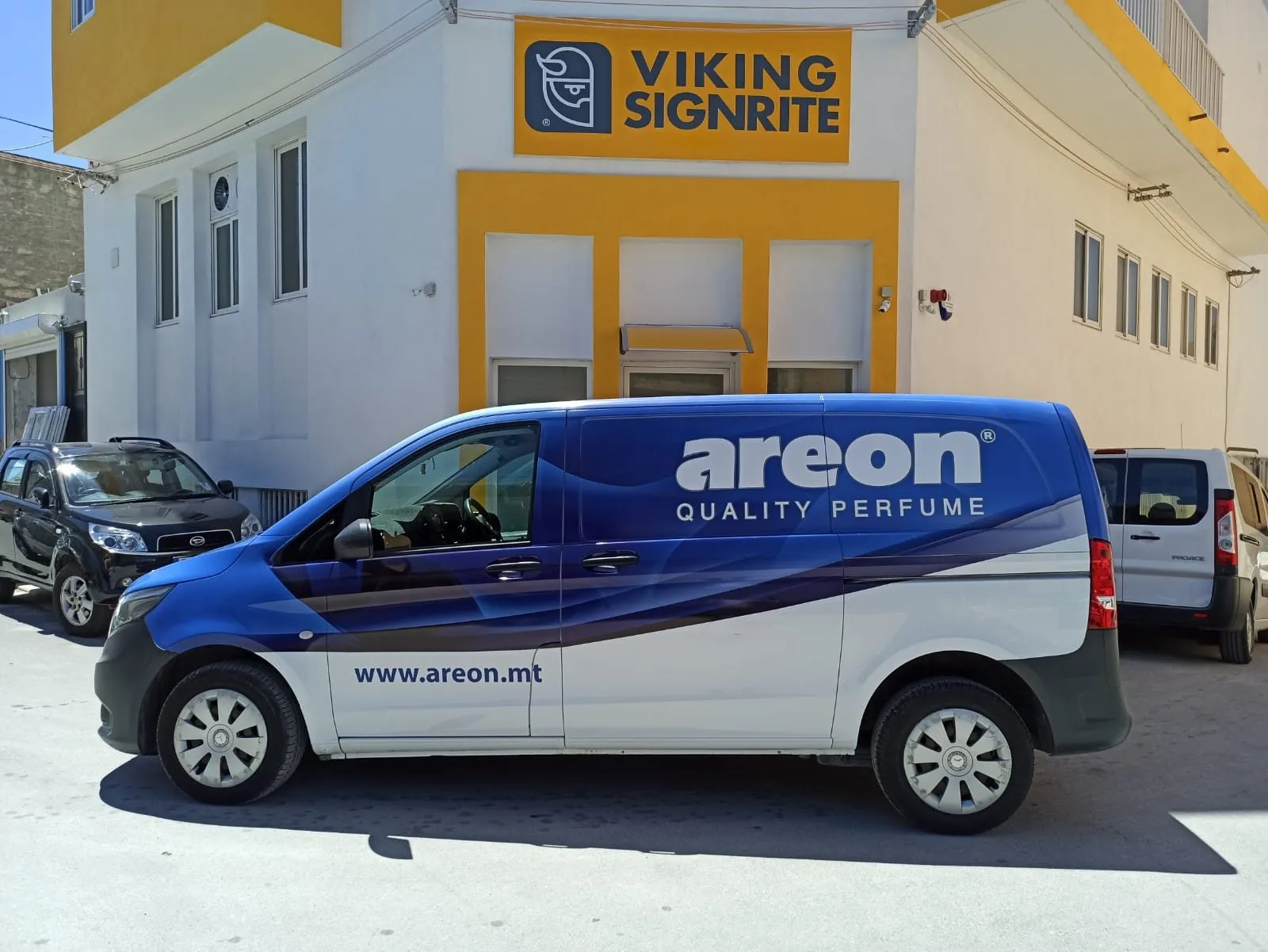 Blue panel van wrapped with a product graphic, parked outside a workshop