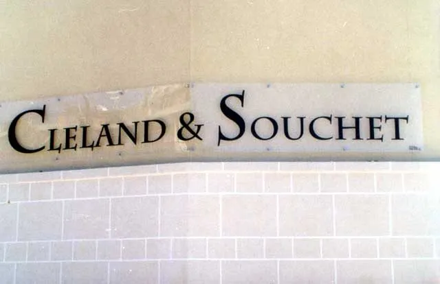 Clear acrylic plate with engraved serif lettering mounted on standoff fixings against white brick