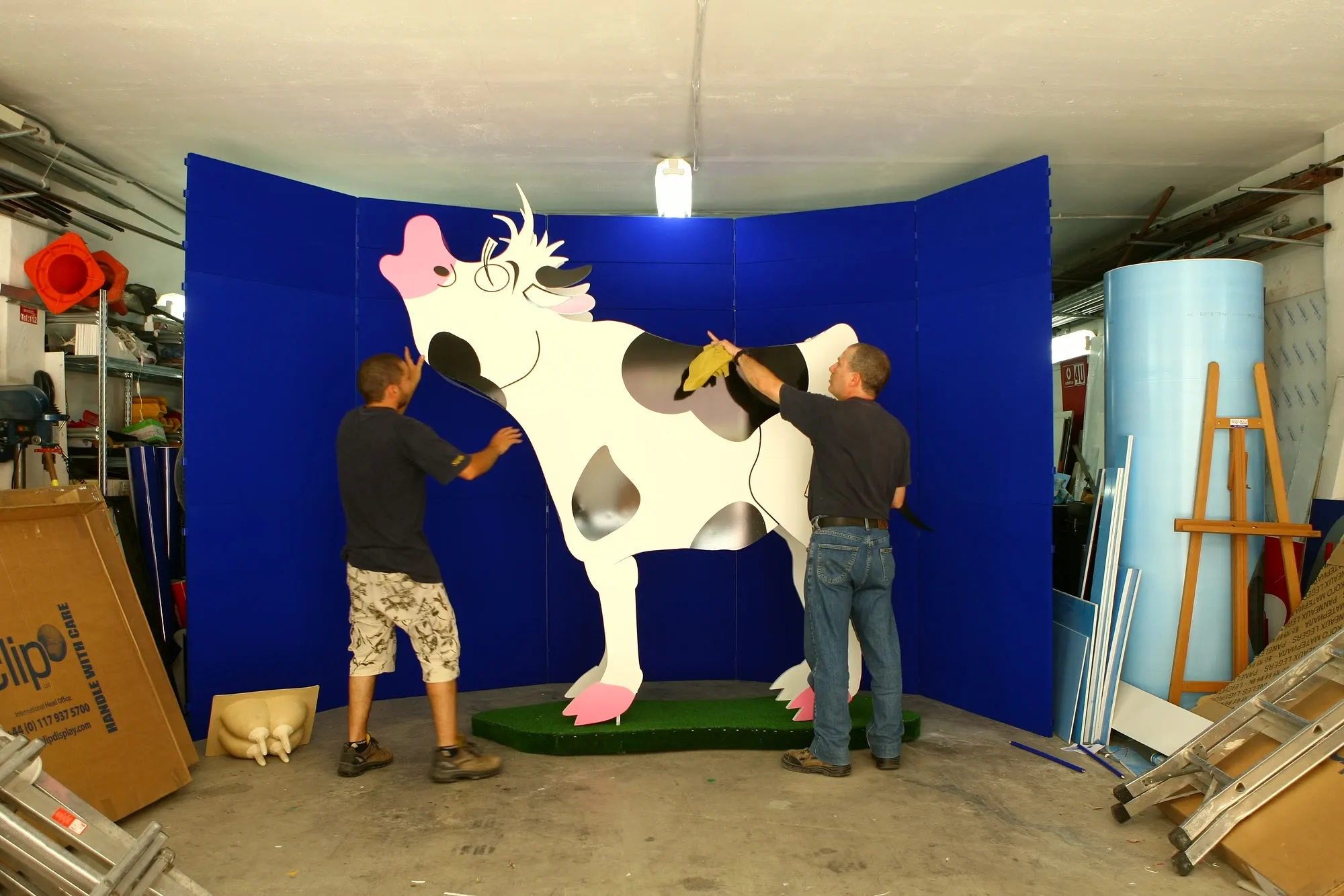 Two workshop technicians applying the surface finish to a full-size fabricated display figure