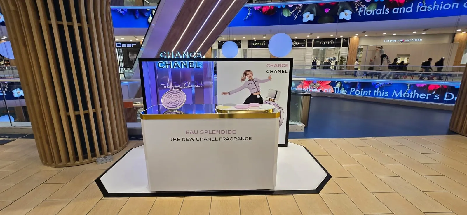 White and gold promotional podium with a printed back panel standing in a shopping centre atrium
