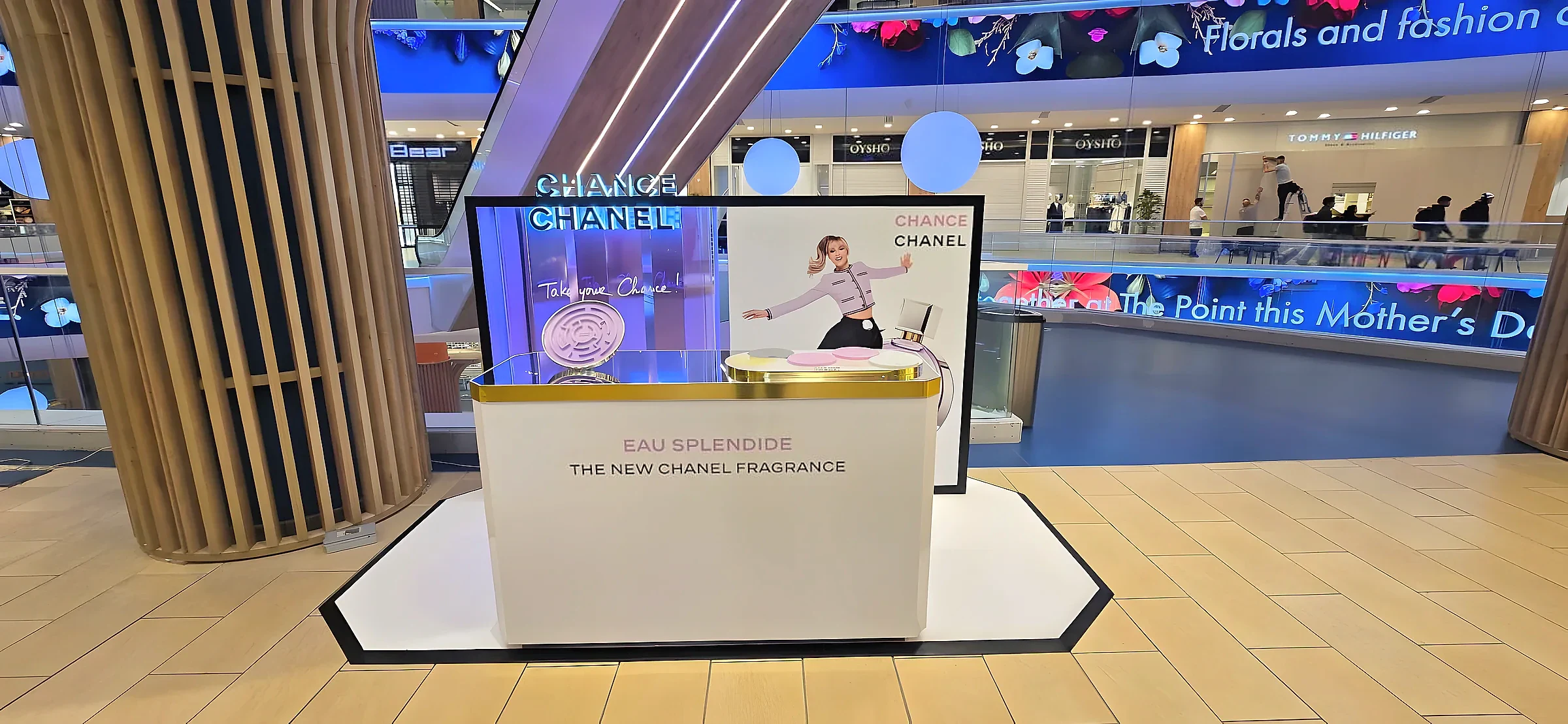 White and gold promotional podium with a printed back panel standing in a shopping centre atrium
