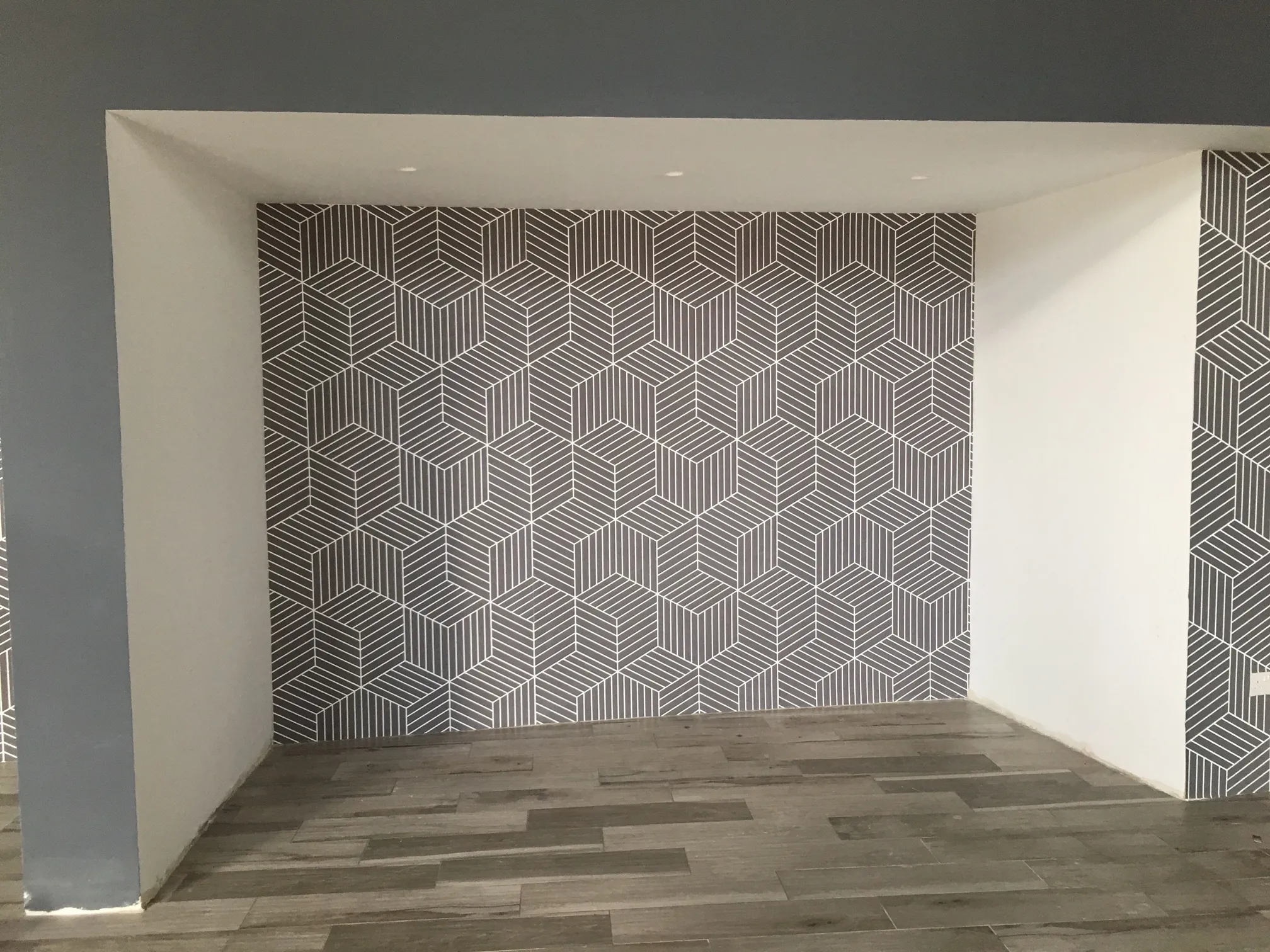 Geometric line-pattern wall covering applied into a recess, running across the back wall and returning onto the side of the opening