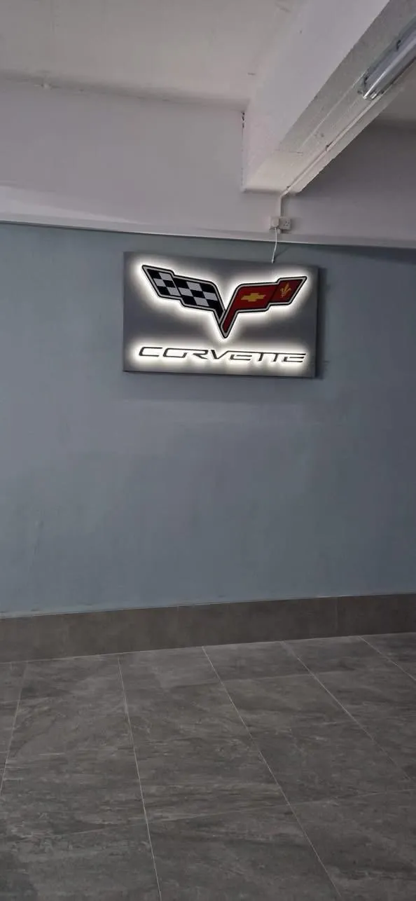Halo-lit car emblem panel glowing on a plain grey interior wall above a tiled floor