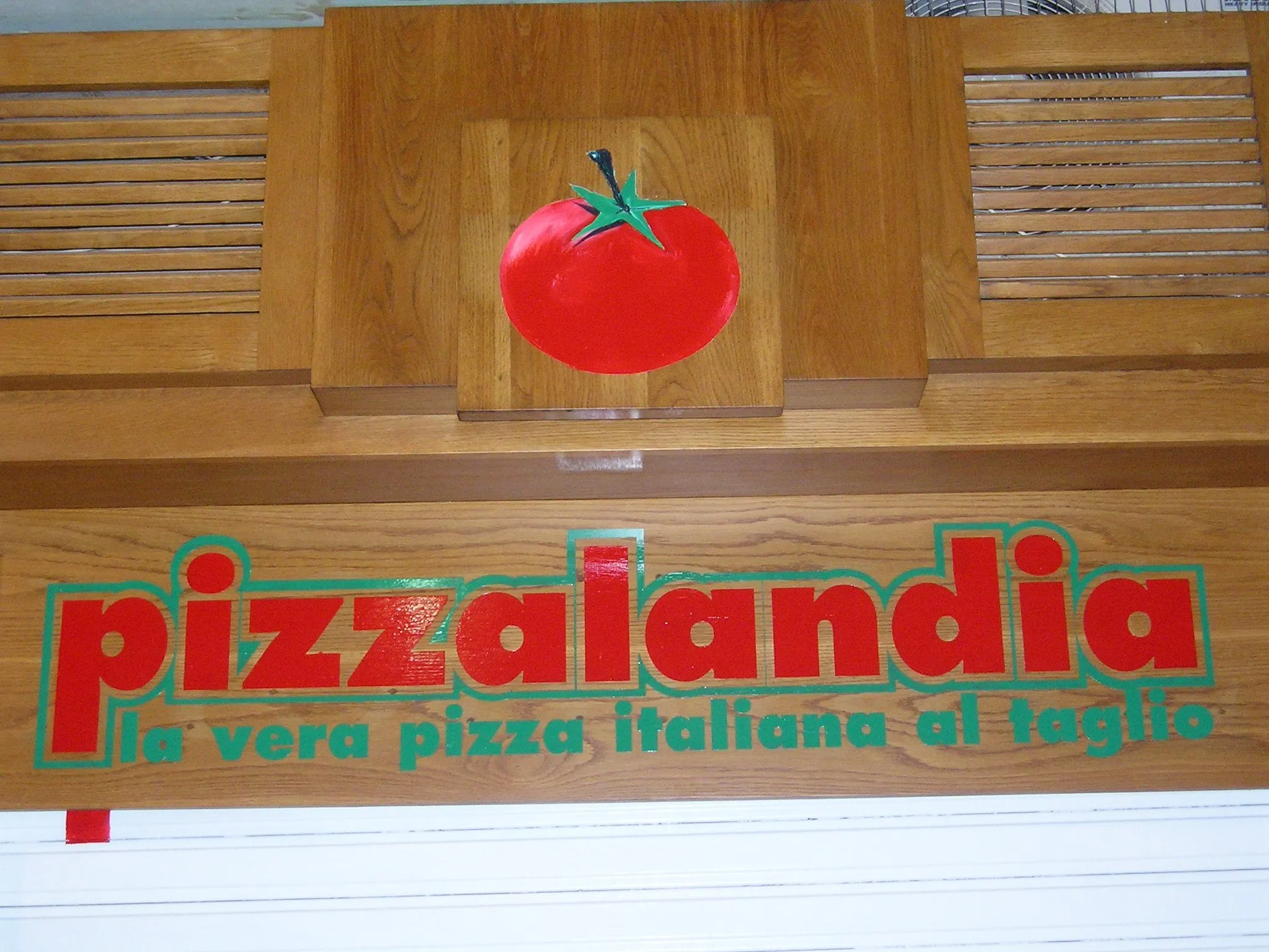 Timber shopfront panel hand-painted with red and green lettering beneath a painted tomato