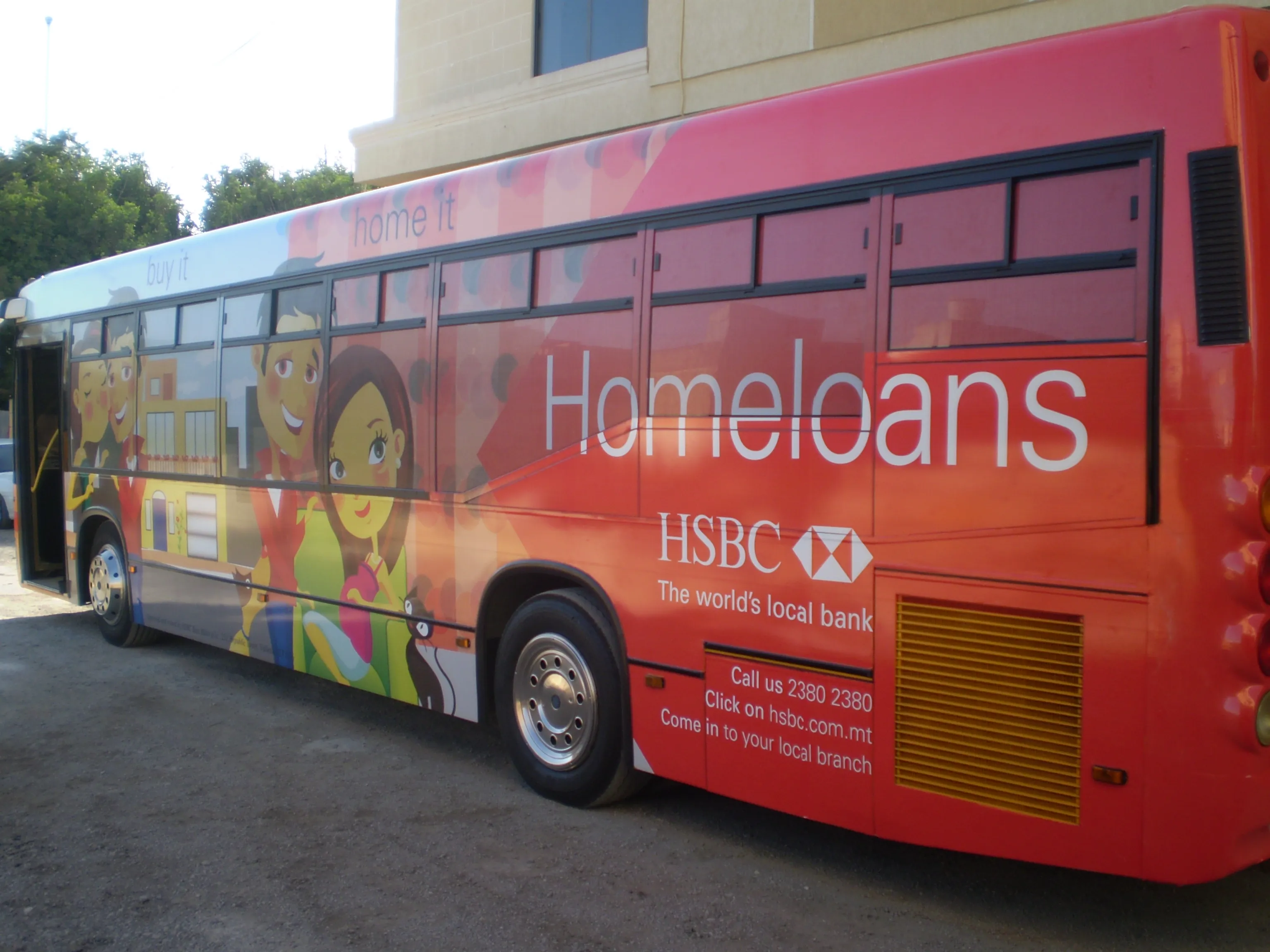 Bus wrapped in a warm illustrated townscape with characters along the lower body, a large headline across the flank and a block of contact lines