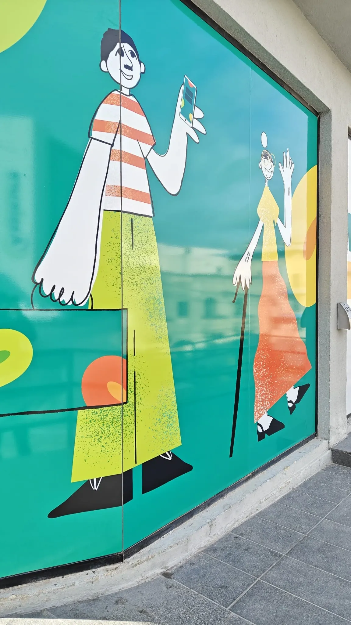 Teal window graphic of two illustrated figures covering the full height of a curved shopfront