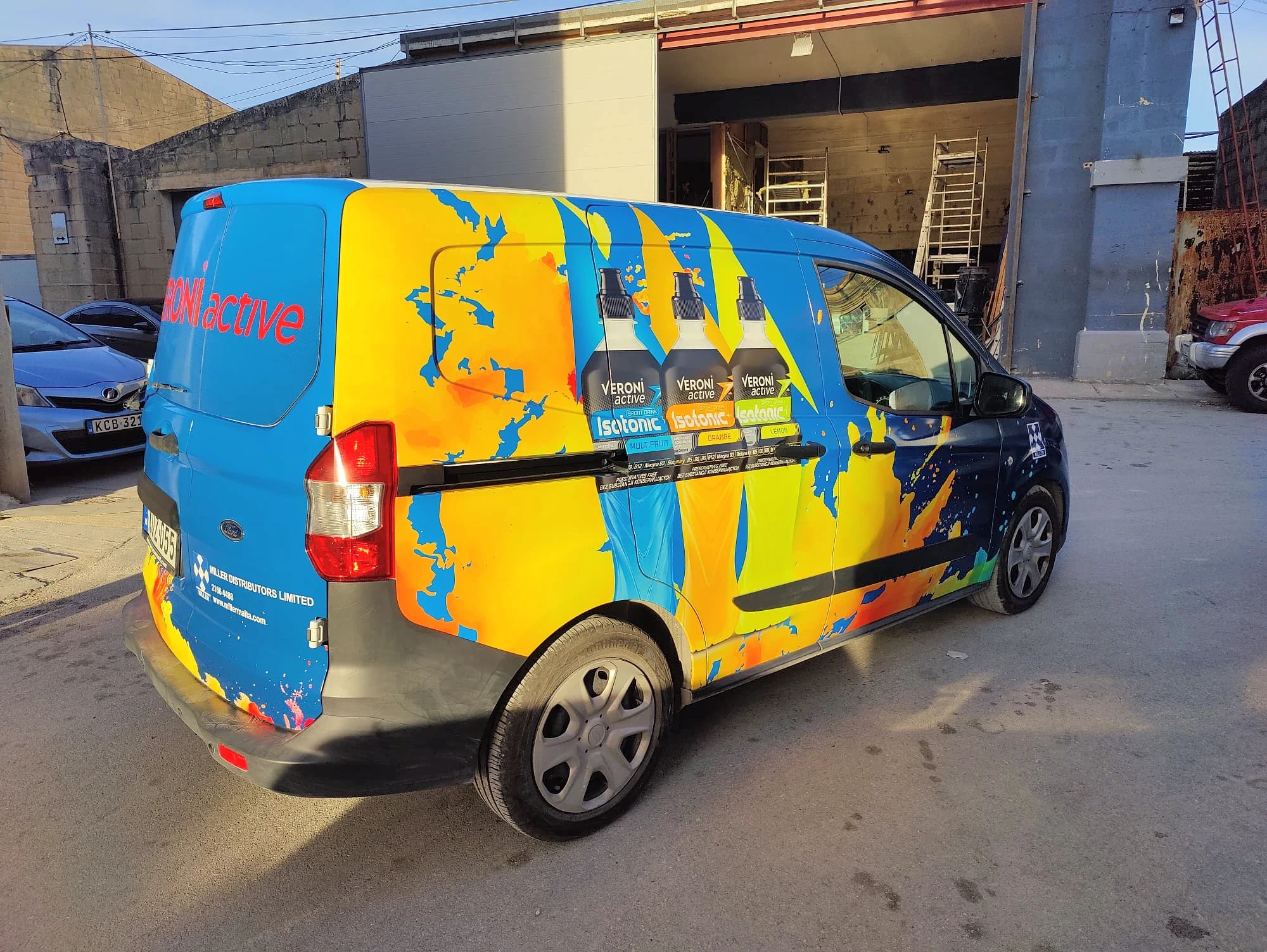Blue, yellow and orange patterned van wrap with three drink bottles printed on the side door