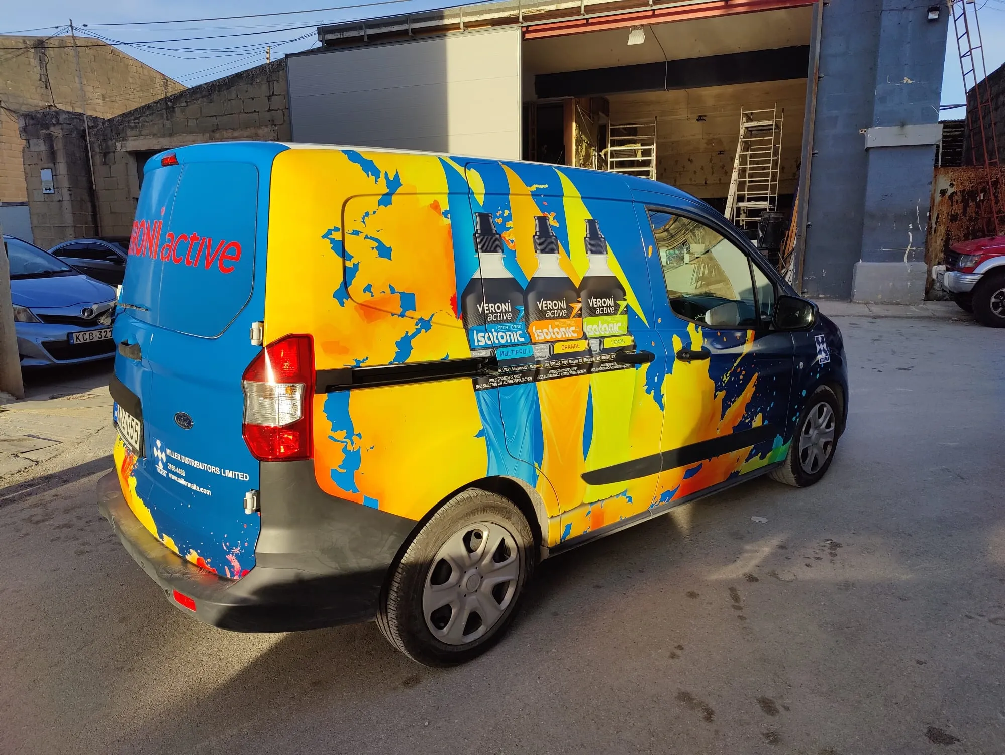 Blue, yellow and orange patterned van wrap with three drink bottles printed on the side door