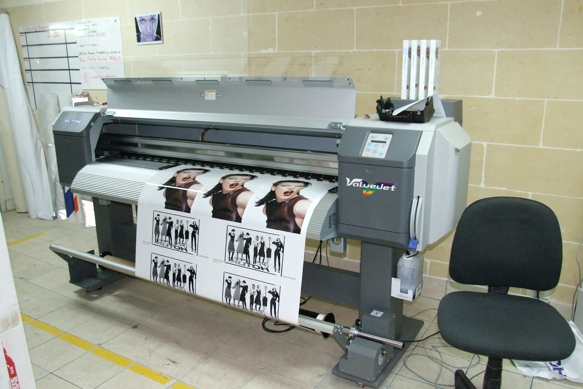 Wide-format printer producing a roll of photographic print media in a workshop