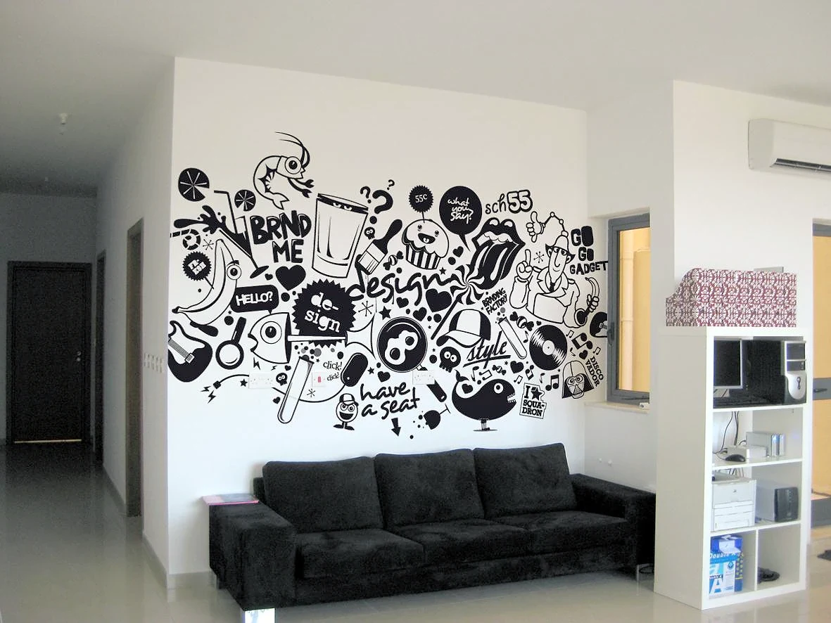 Black doodle-style line-art mural covering a white wall above a black sofa in an office lounge