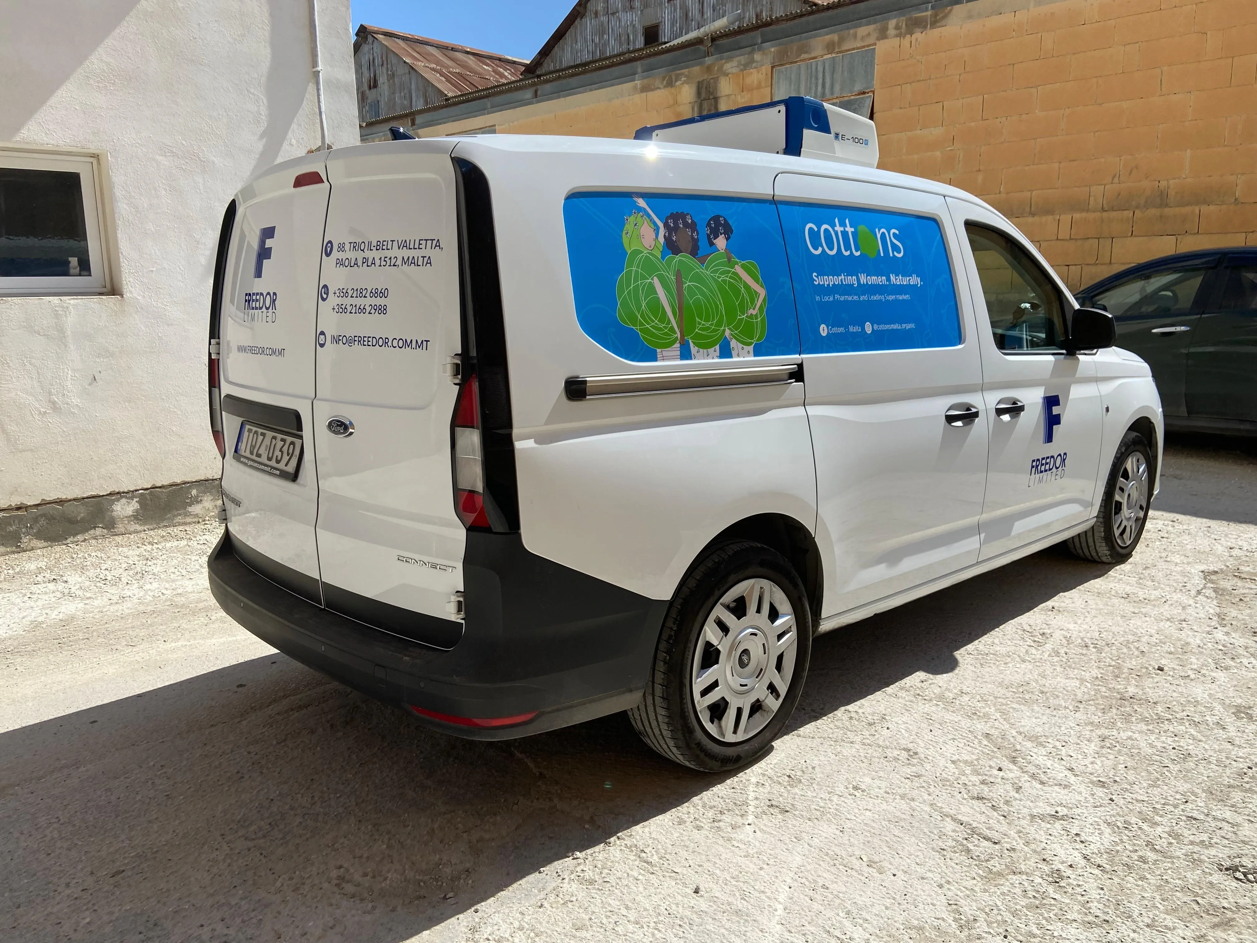 White van with a blue company mark, address text and an illustrated blue panel on the sliding door