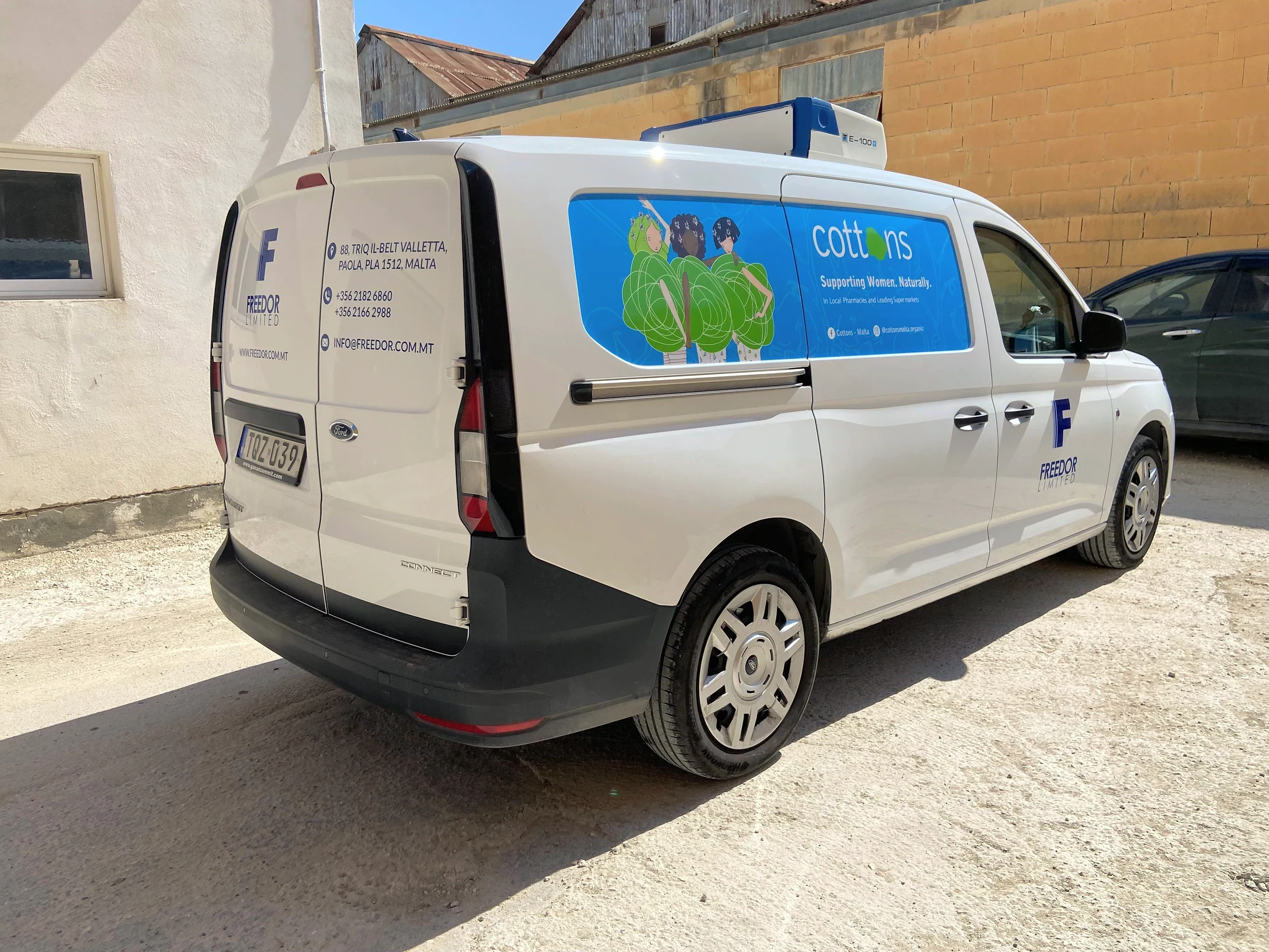 White van with a blue company mark, address text and an illustrated blue panel on the sliding door