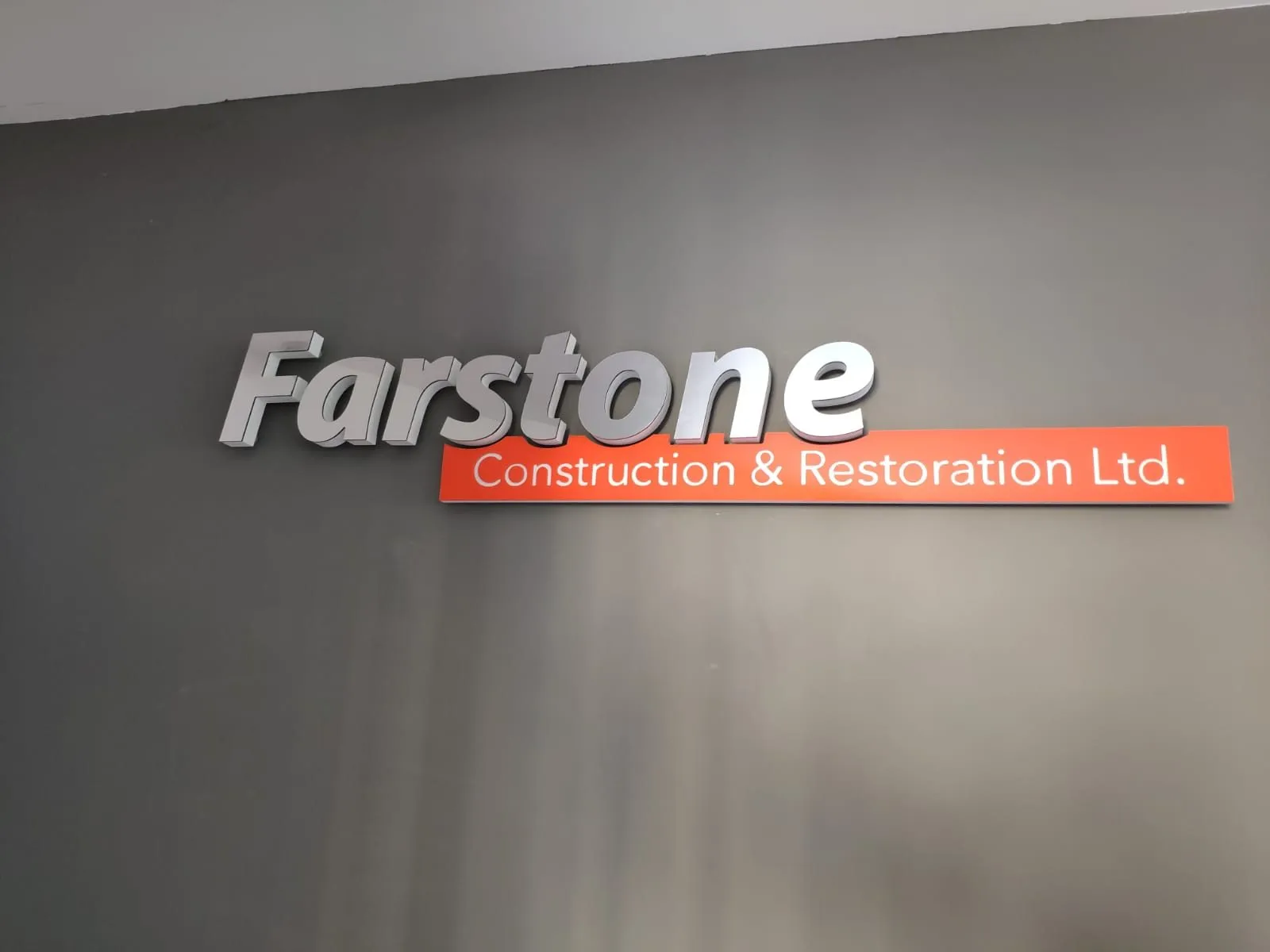 Silver and red raised lettering mounted on a dark grey interior wall