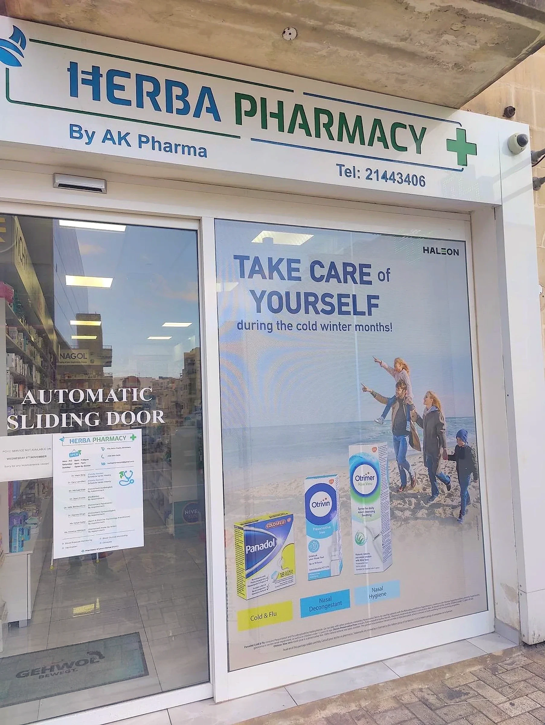 Printed one-way vision window panel showing a seasonal health campaign beside a pharmacy fascia sign