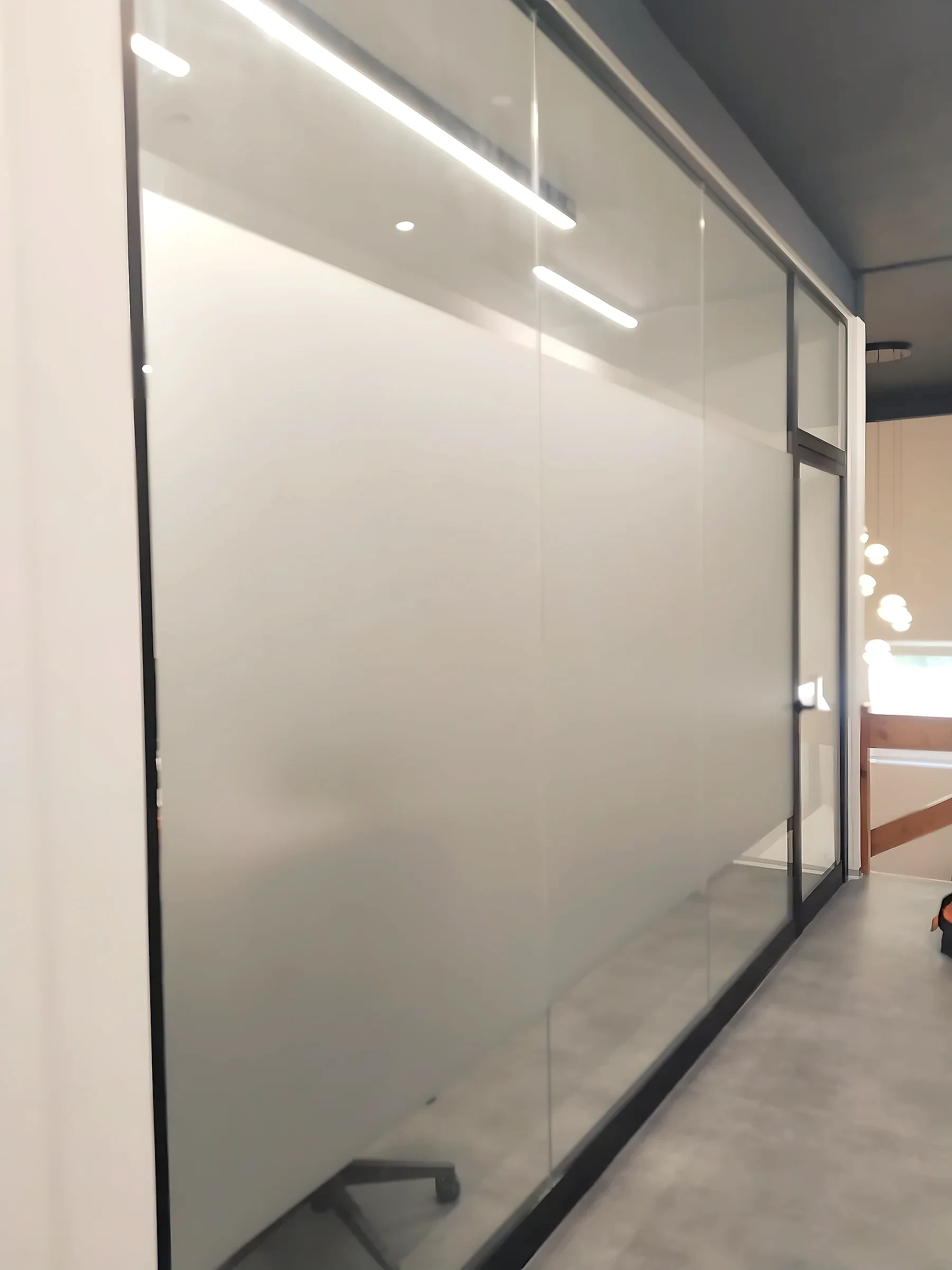Full-height glass office wall covered in plain frosted film with a clear strip above