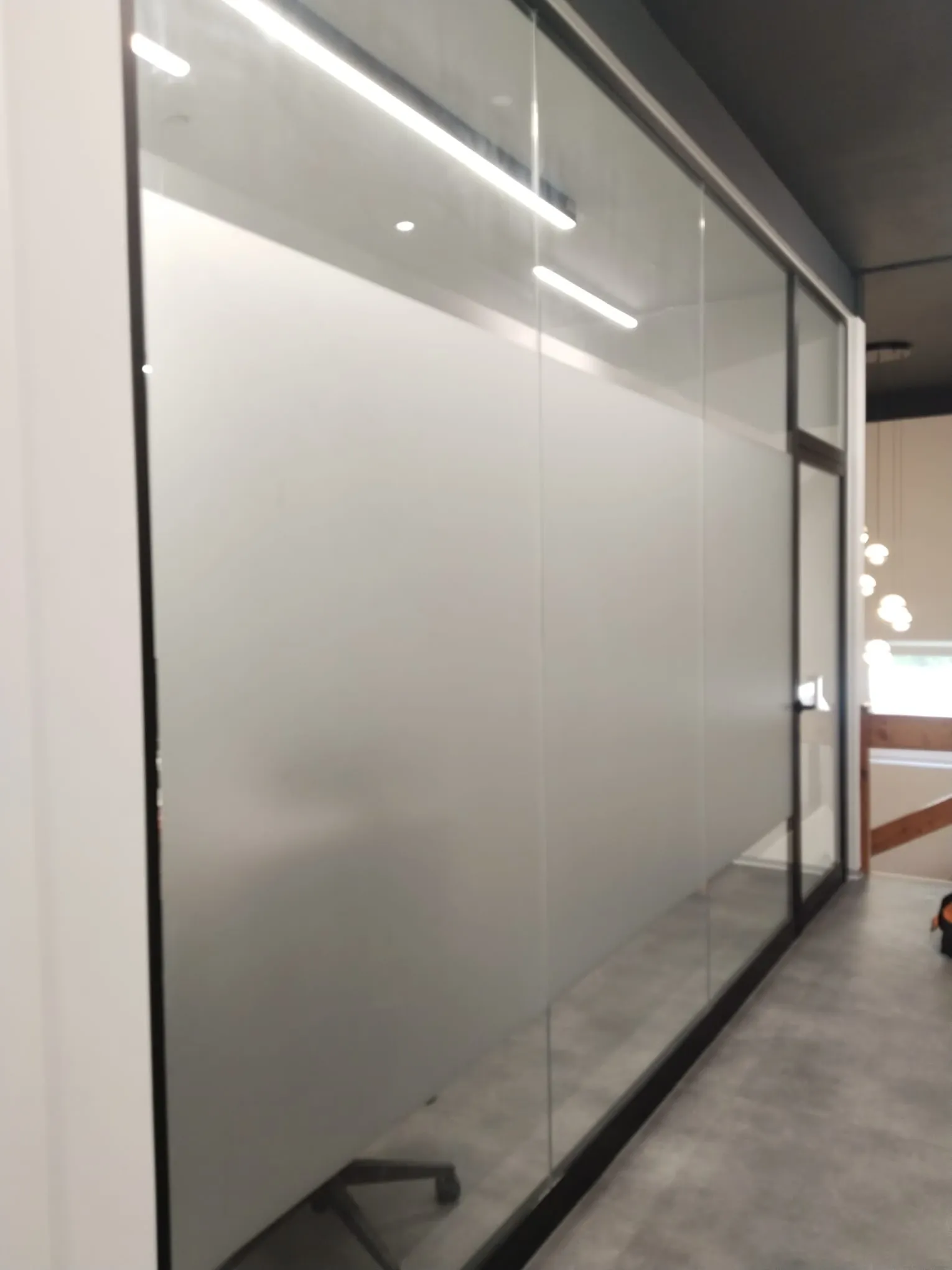 Full-height glass office wall covered in plain frosted film with a clear strip above