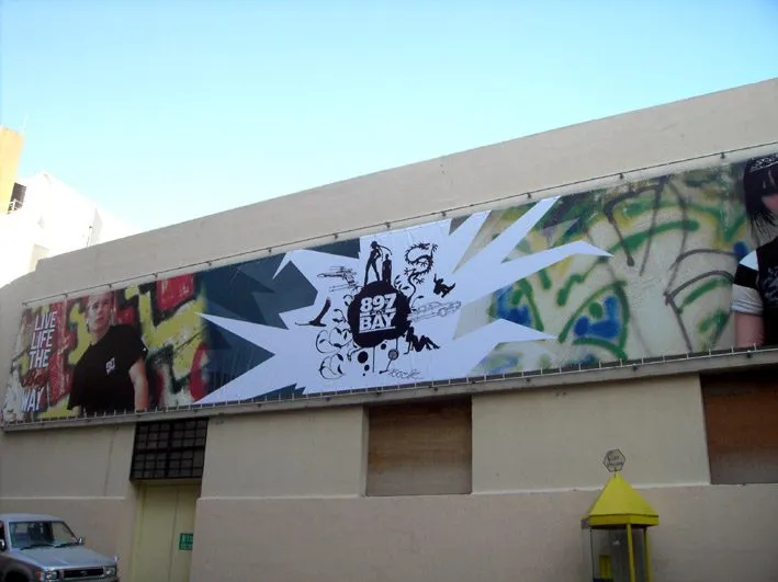 Wide printed banner with illustrated artwork tensioned across a stone building facade