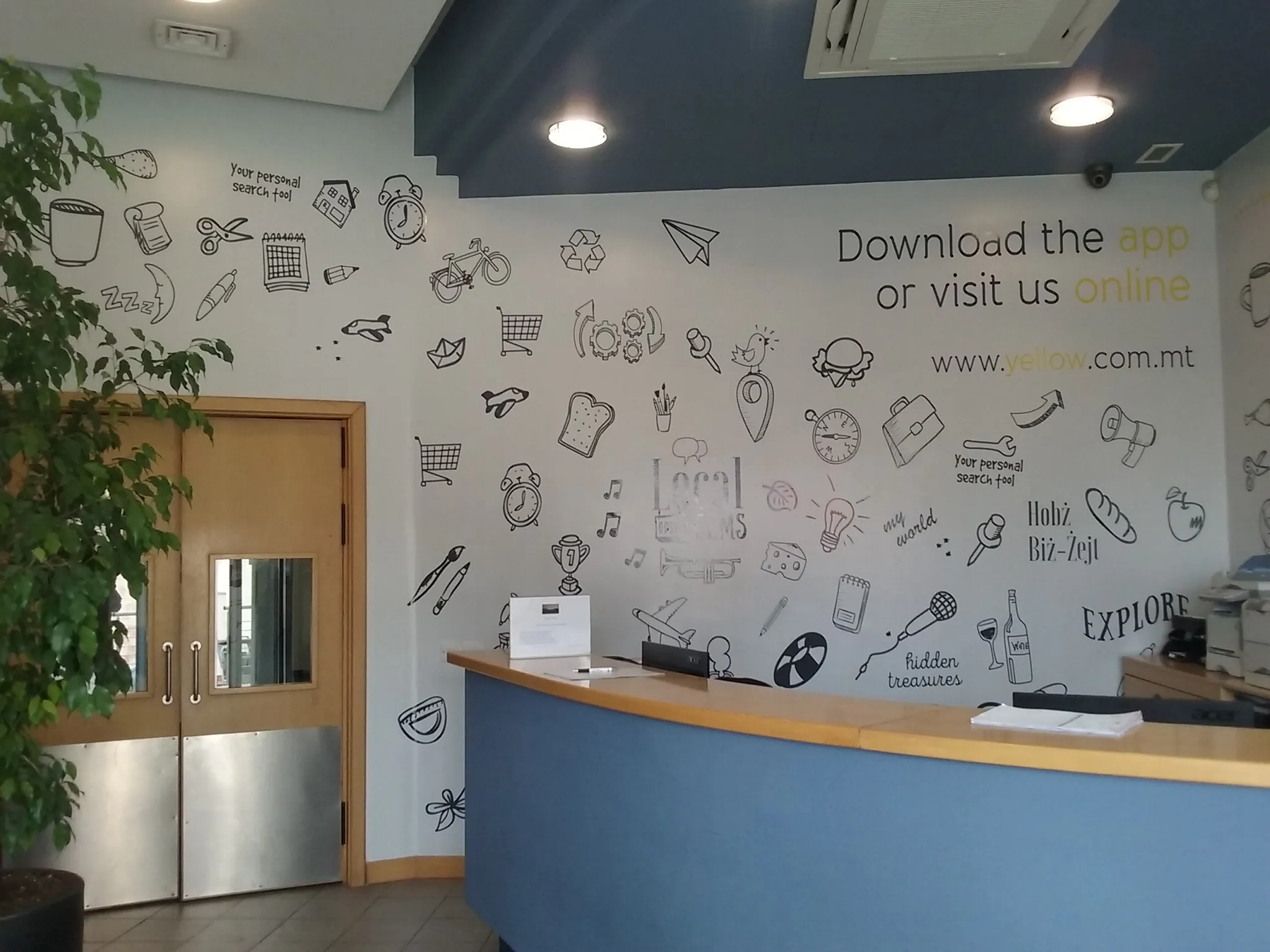 Reception wall covered in scattered hand-drawn line icons with a call-to-action headline and web address set in the upper corner, behind a curved counter