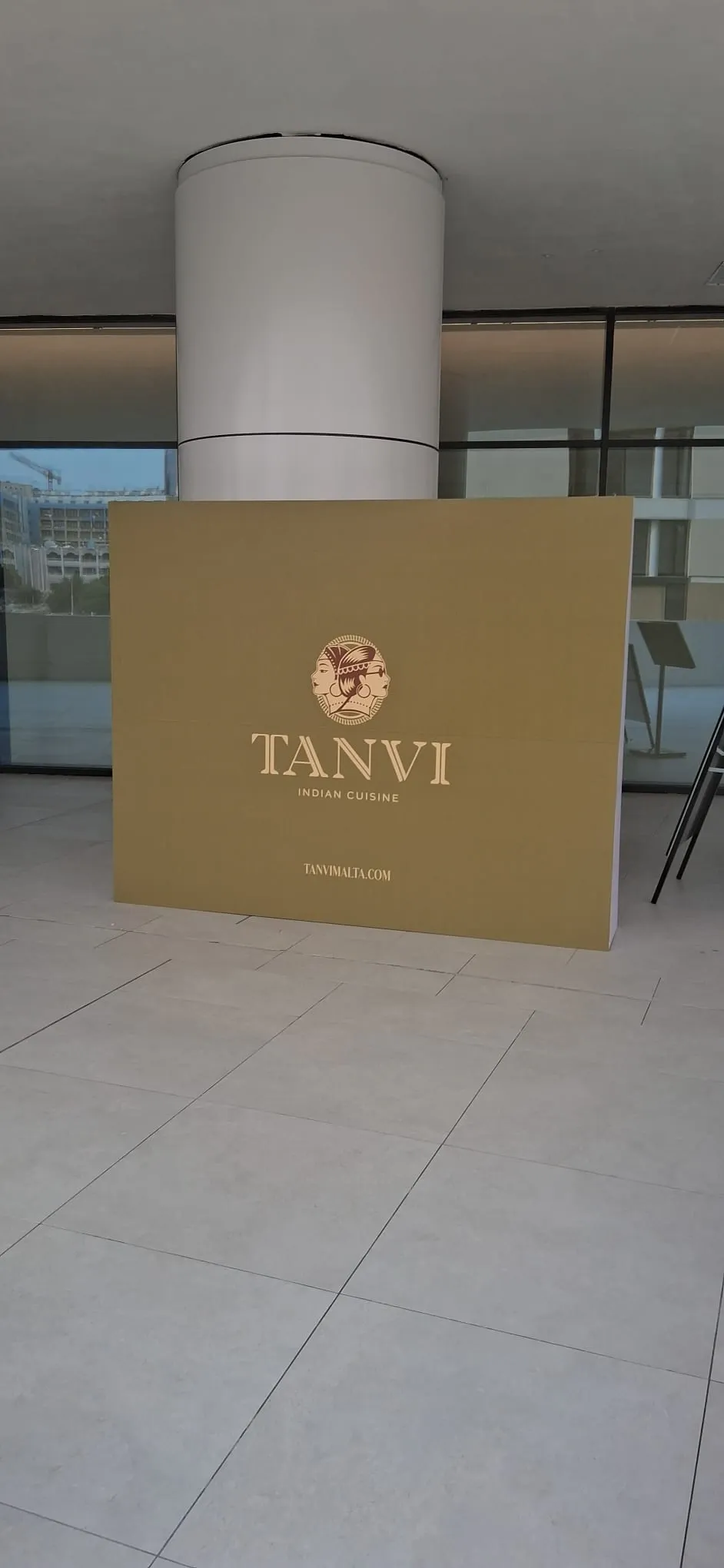 Gold branded plinth panel for an Indian restaurant standing in a tiled lobby