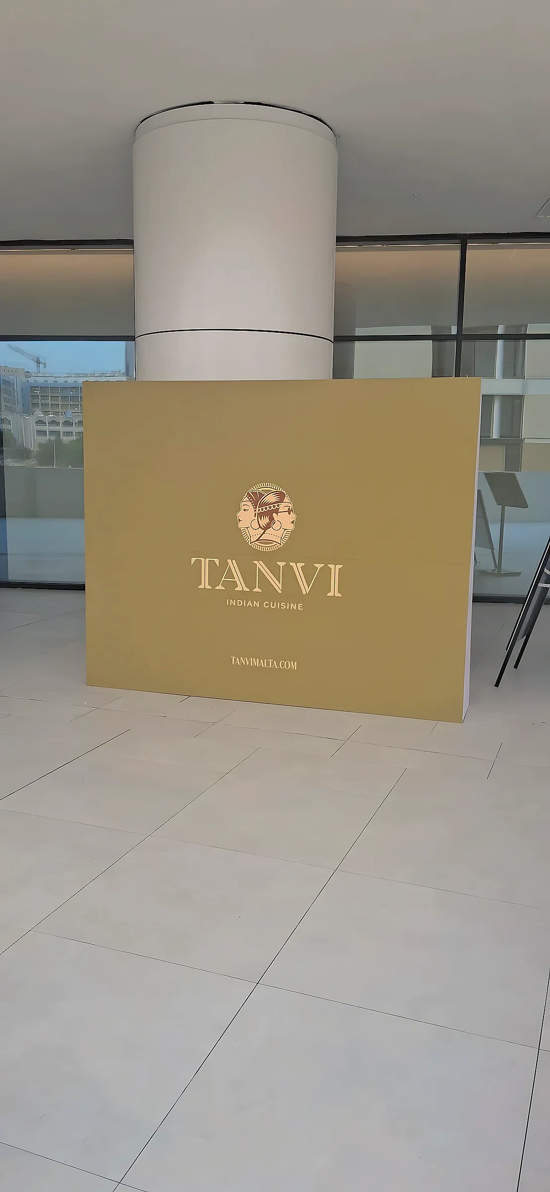 Gold branded plinth panel for an Indian restaurant standing in a tiled lobby