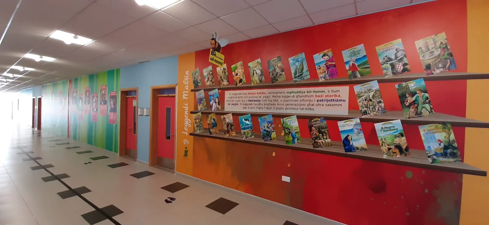 A further section of the same corridor in warm colours, with a text panel and book display shelving fitted over the printed wall