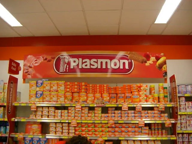 Retail bay with an orange printed header panel above shelves stocked with cartons and jars