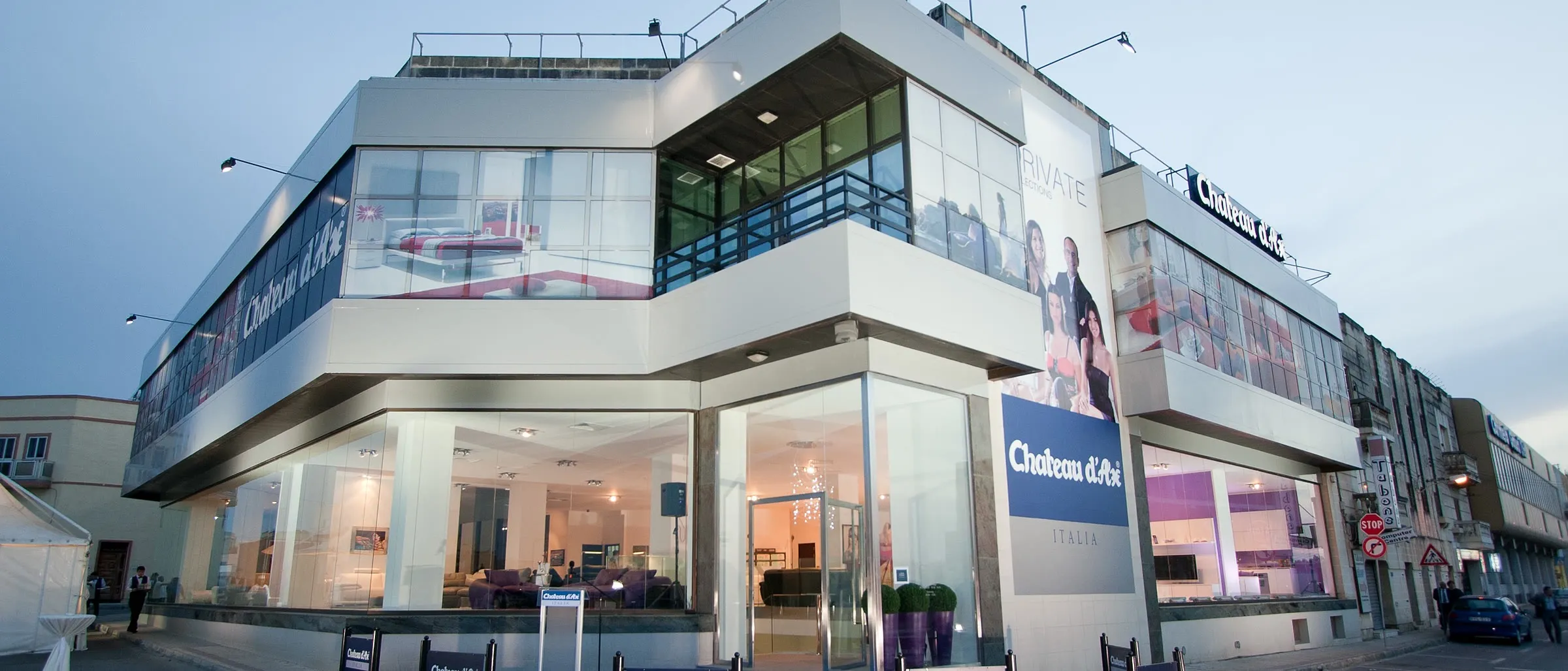 Two-storey retail showroom with facade signs, window graphics and blue perimeter panels in daylight