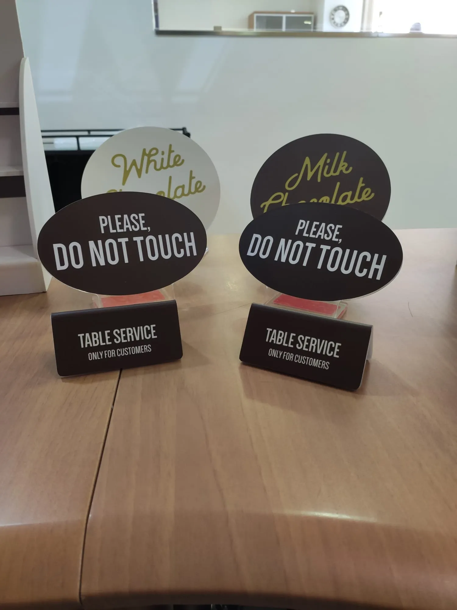 Two oval tabletop signs reading please do not touch on printed table service bases