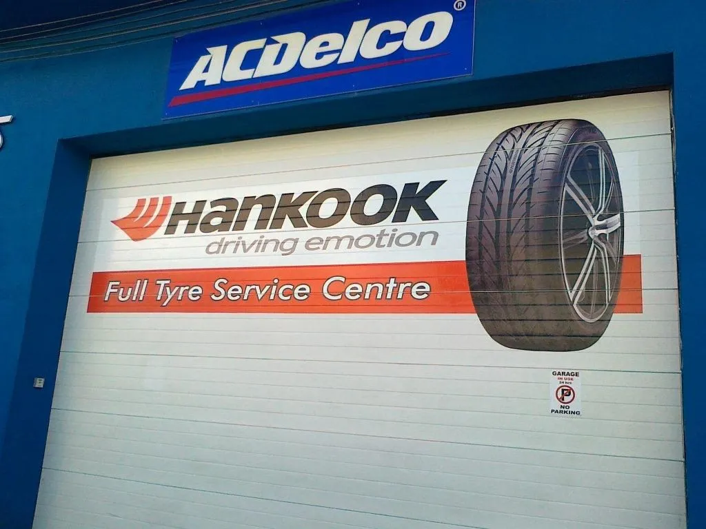 Roller shutter printed with a tyre graphic below a blue fascia panel at a service centre entrance
