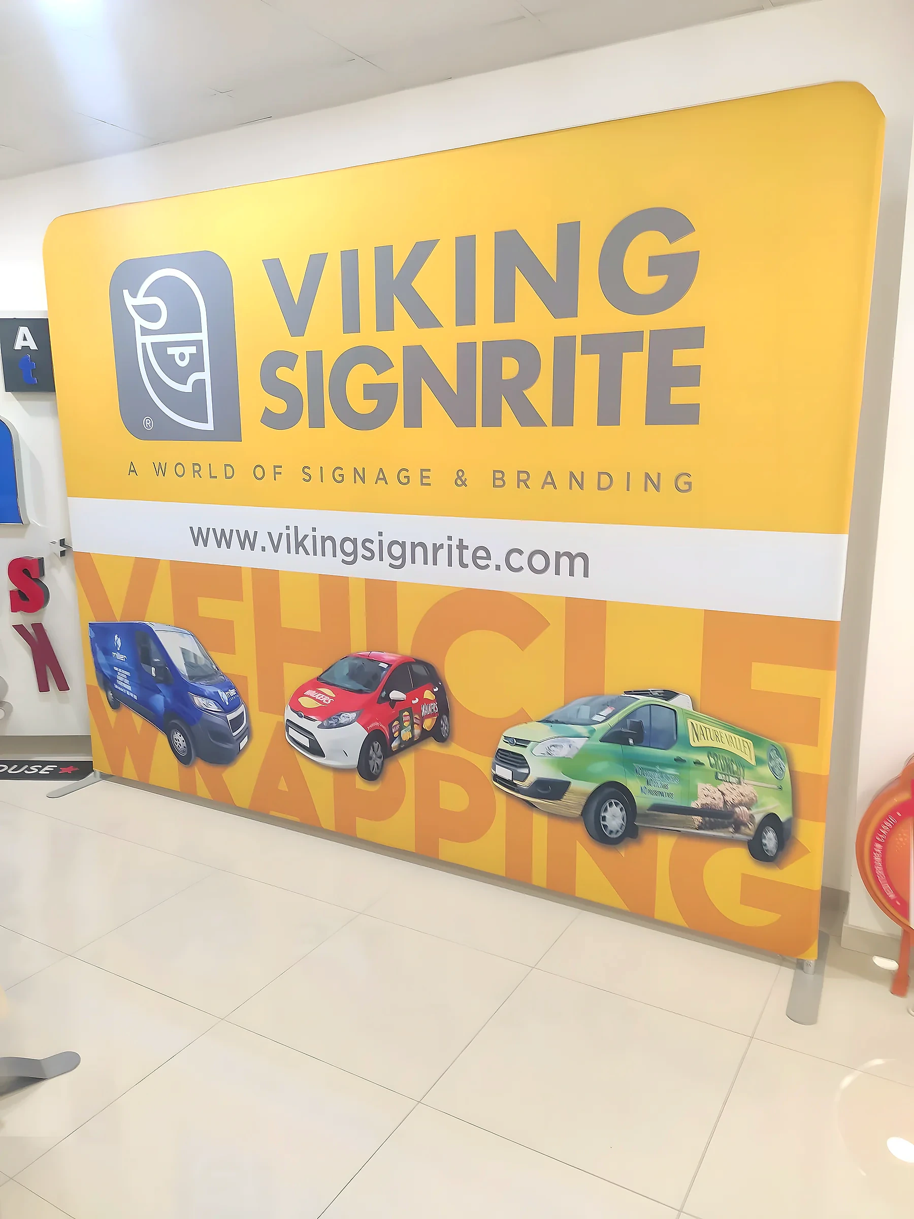Yellow Viking Signrite fabric display wall showing three wrapped vehicles, standing in the workshop