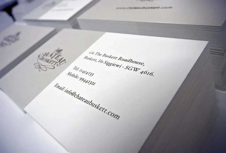 Close view of a cream letterpress-style business card printed with a restaurant's address and contact details