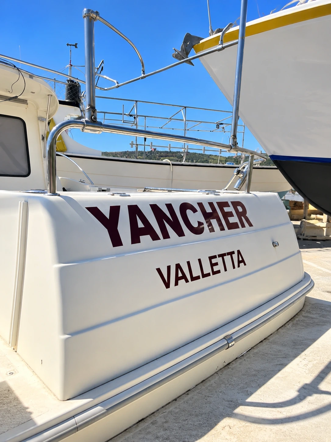 Cut vinyl boat name and port lettering applied across the transom of a yacht in a boatyard
