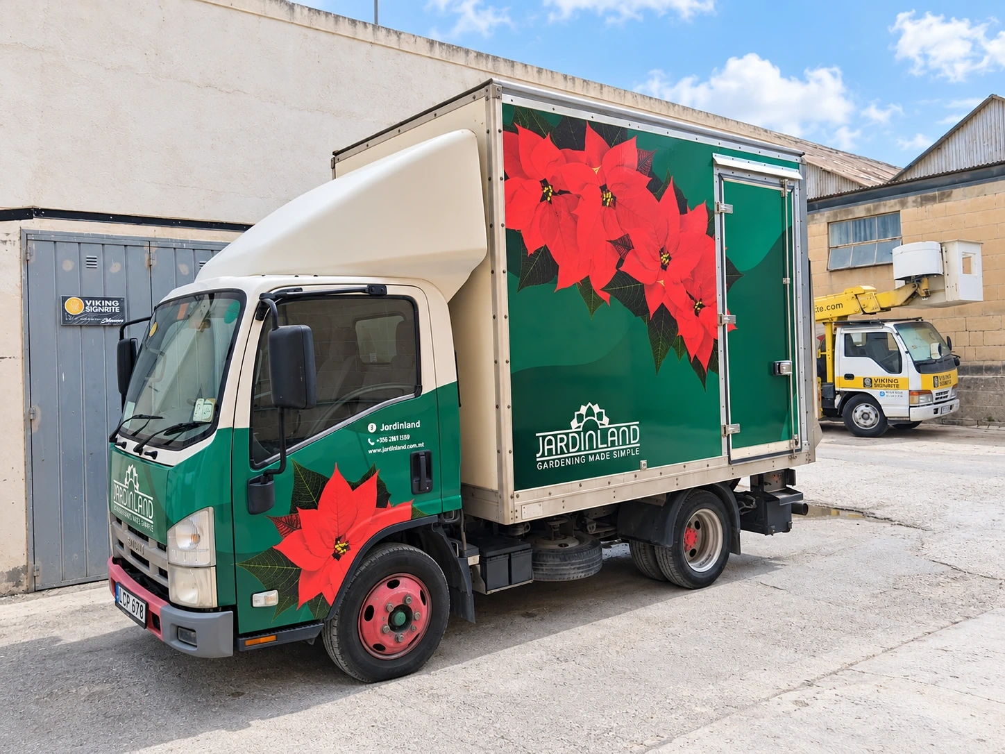Box truck wrapped in deep green with large printed poinsettia flowers along the body