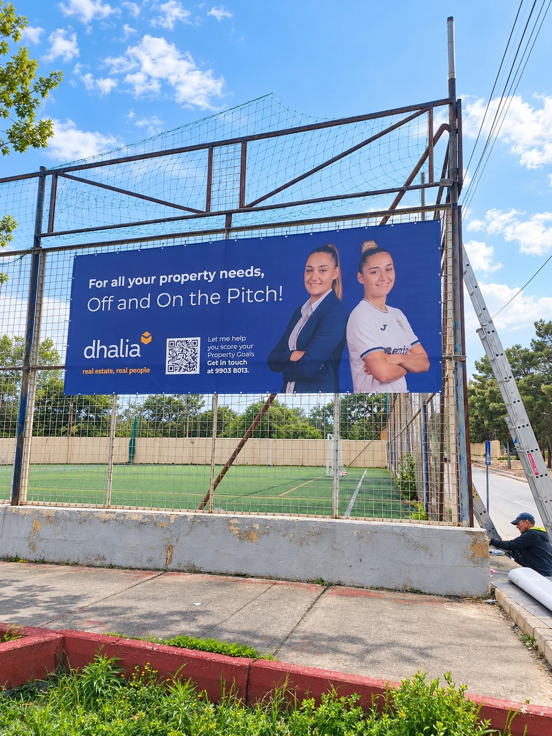 Printed banner tensioned onto the fence of a floodlit sports pitch