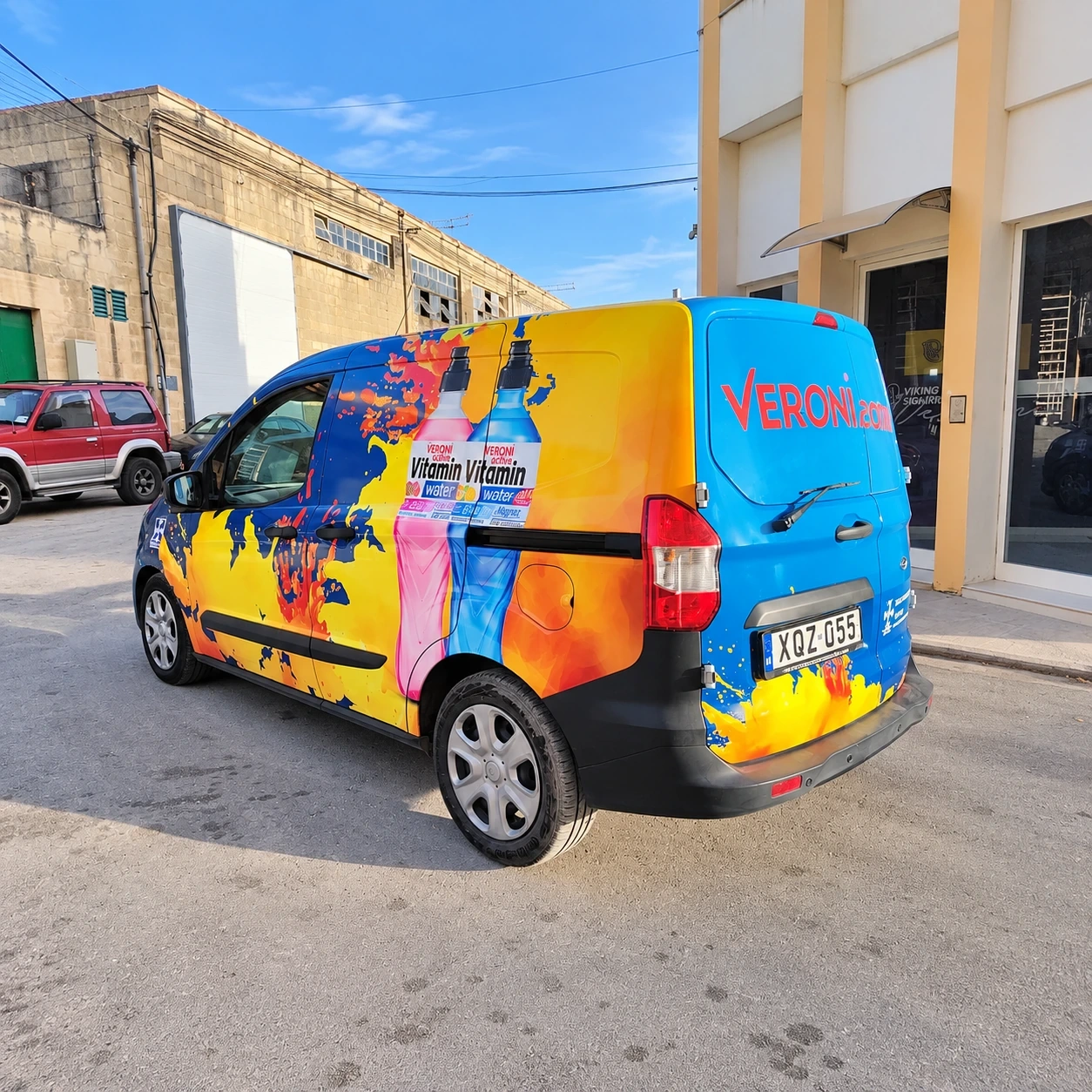 Compact van wrapped in a bright orange and blue pattern with printed drink bottles
