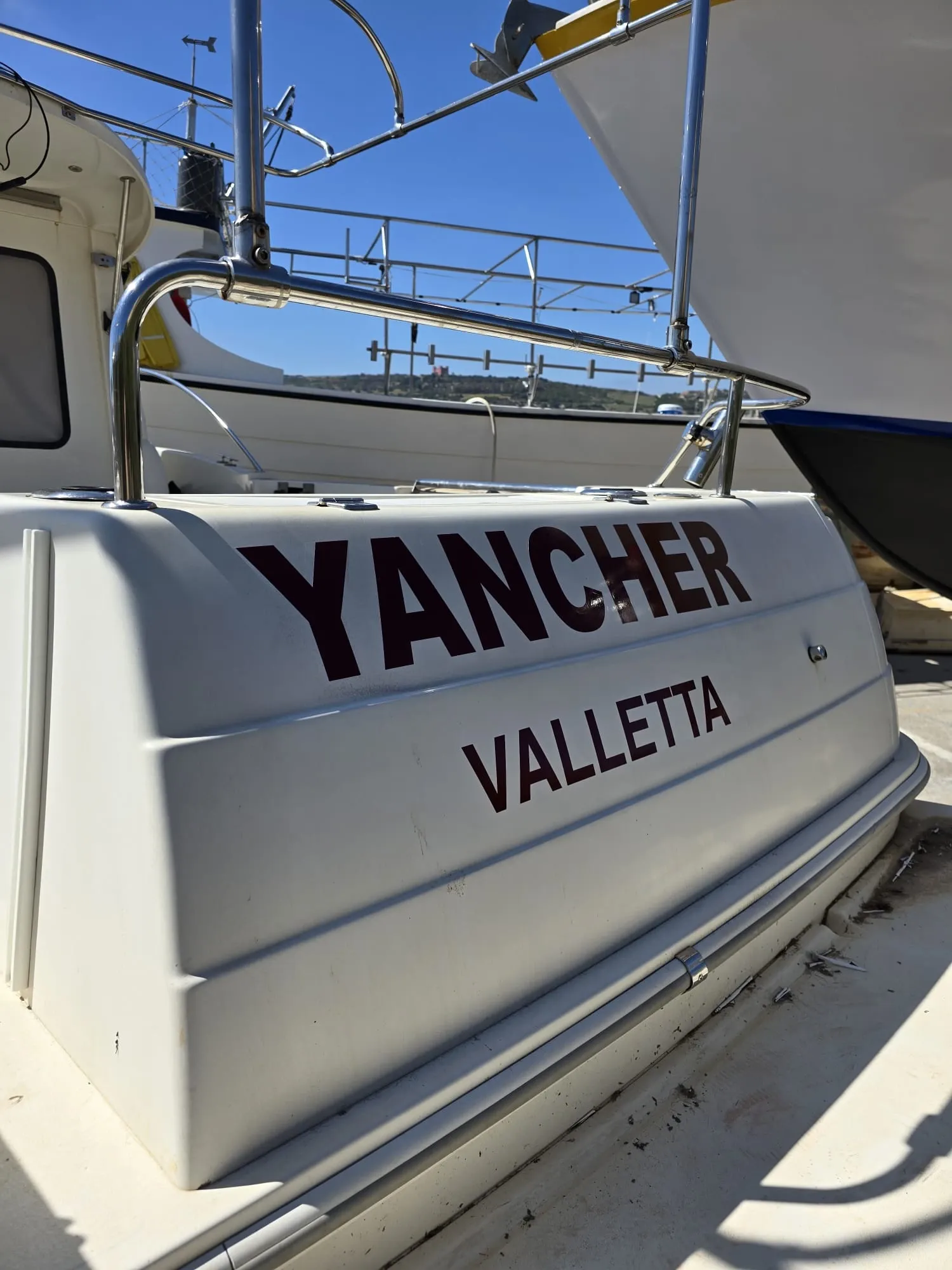 Cut vinyl boat name and port lettering applied across the transom of a yacht in a boatyard