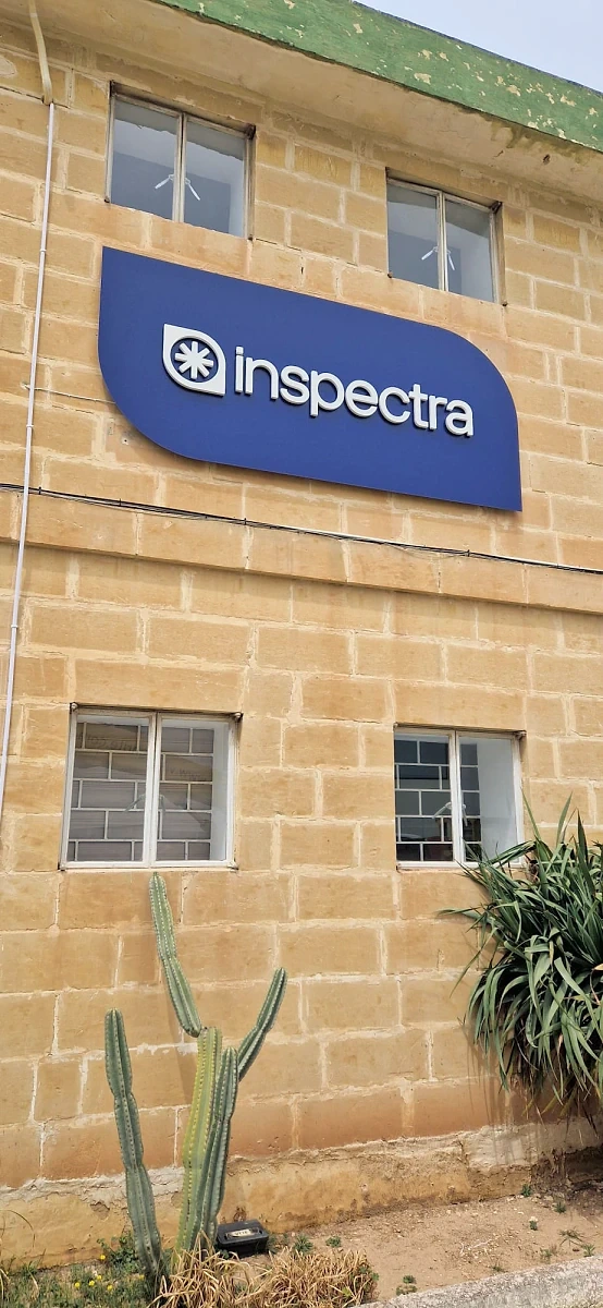 Blue shaped fascia sign mounted high on a limestone building above two windows
