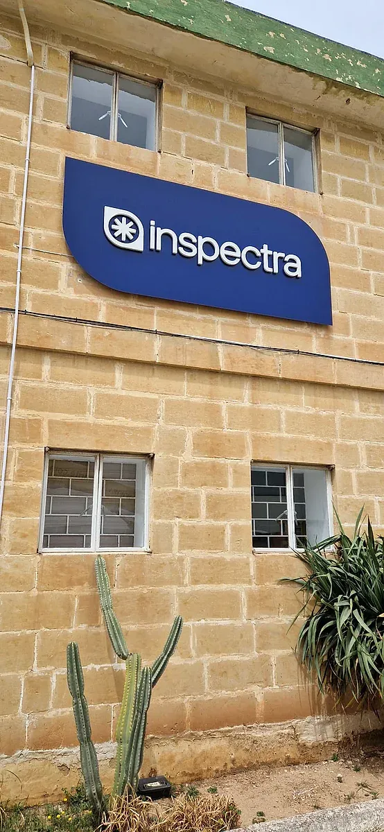 Blue shaped fascia sign mounted high on a limestone building above two windows